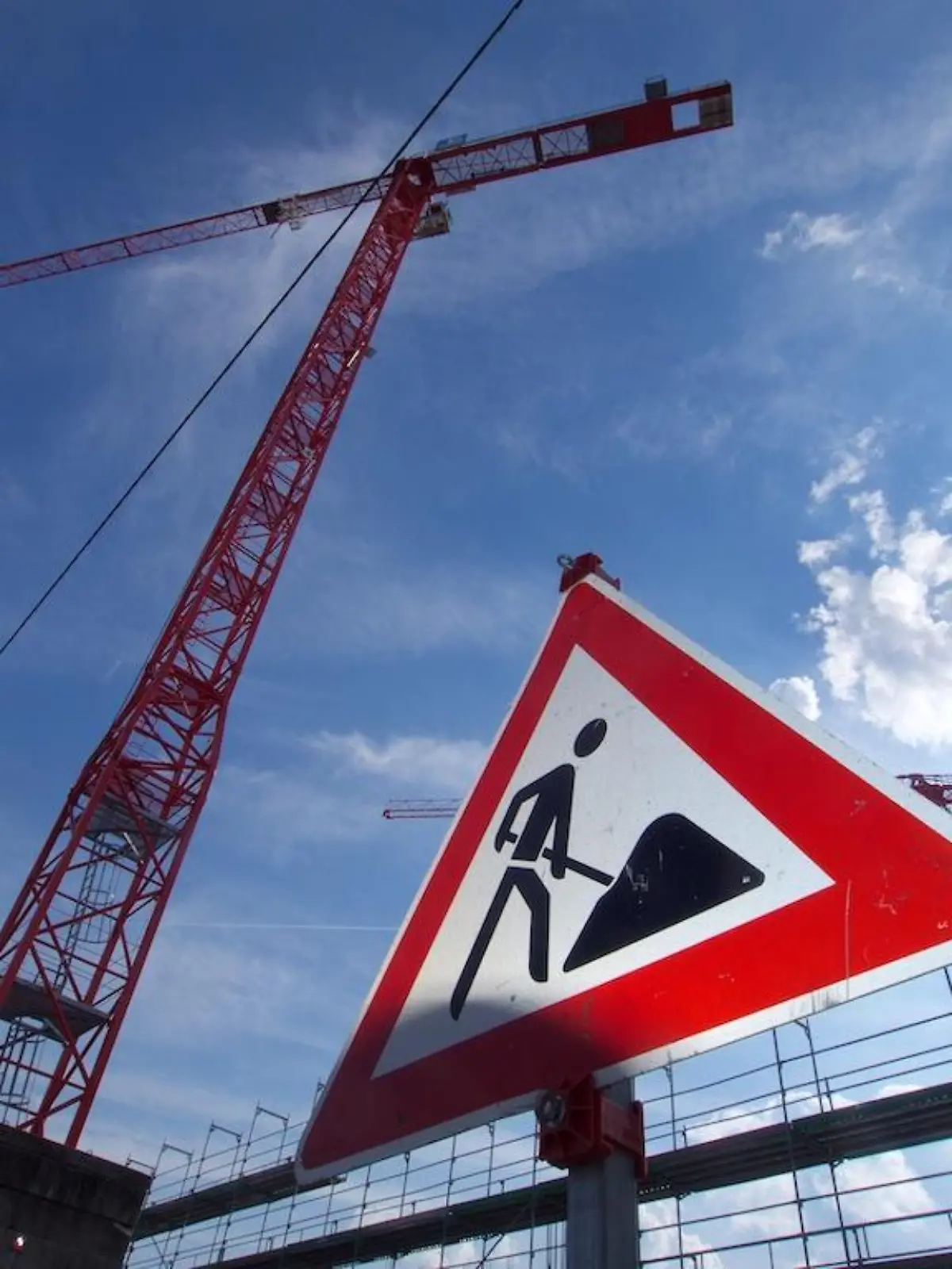 ARCHIV - 15.04.2022, Bayern, München: Ein Baustellenschild und Baukräne im Münchner Stadteil Freiham. Nach mehr als zehn Jahren Immobilienboom in Deutschland und enorm steigenden Preisen erwarten einige Experten eine Wende am Wohnungsmarkt. (zu dpa "Zinsanstieg, teures Bauen, Lieferengpässe - Kippt der Immobilienboom?") Foto: Carsten Hoefer/dpa +++ dpa-Bildfunk +++