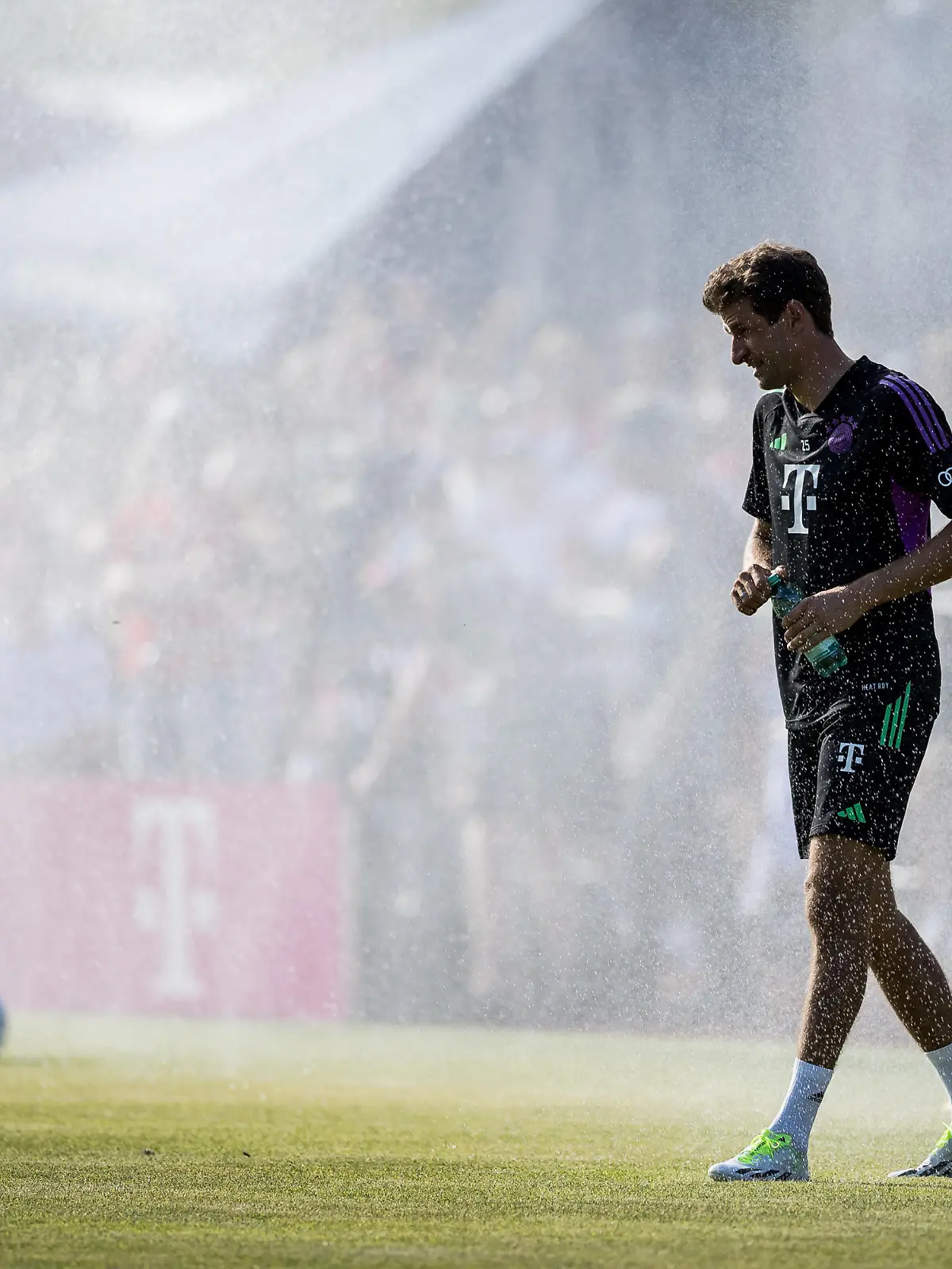Thomas Mueller (FC Bayern Muenchen, #25) laeuft lachend durch den Rasensprenger Oeffentliches Training FC Bayern Muenchen; Sportplatz Rottach-Egern, 15.07.2023