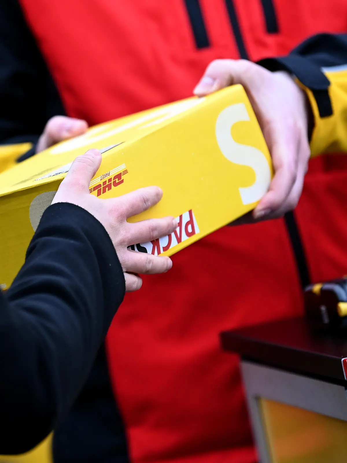 Eine junge Frau gibt bei Mitarbeitern am DHL-Paketbus ein Paket ab während eines Presse- und Fototermins zur Präsentation des Buses (gestellte Szene). An mehreren Berliner Standorten stehen die Busse den Bürgerinnen und Bürgern als DHL-Paketshops zur Verfügung.