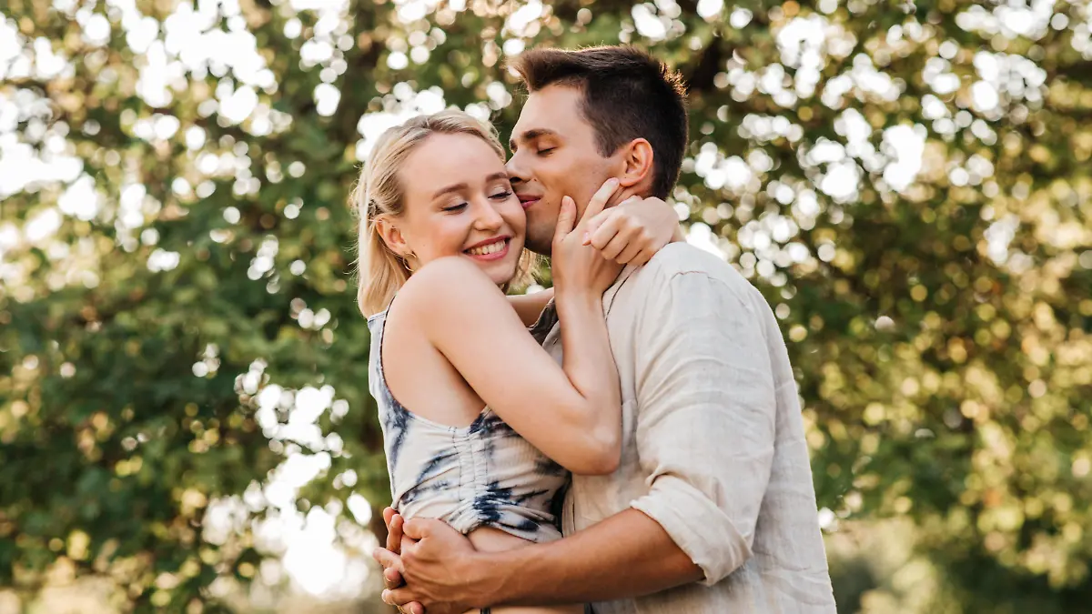 summer holidays, love and people concept - happy young couple kissing and hugging outdoors || Modellfreigabe vorhanden