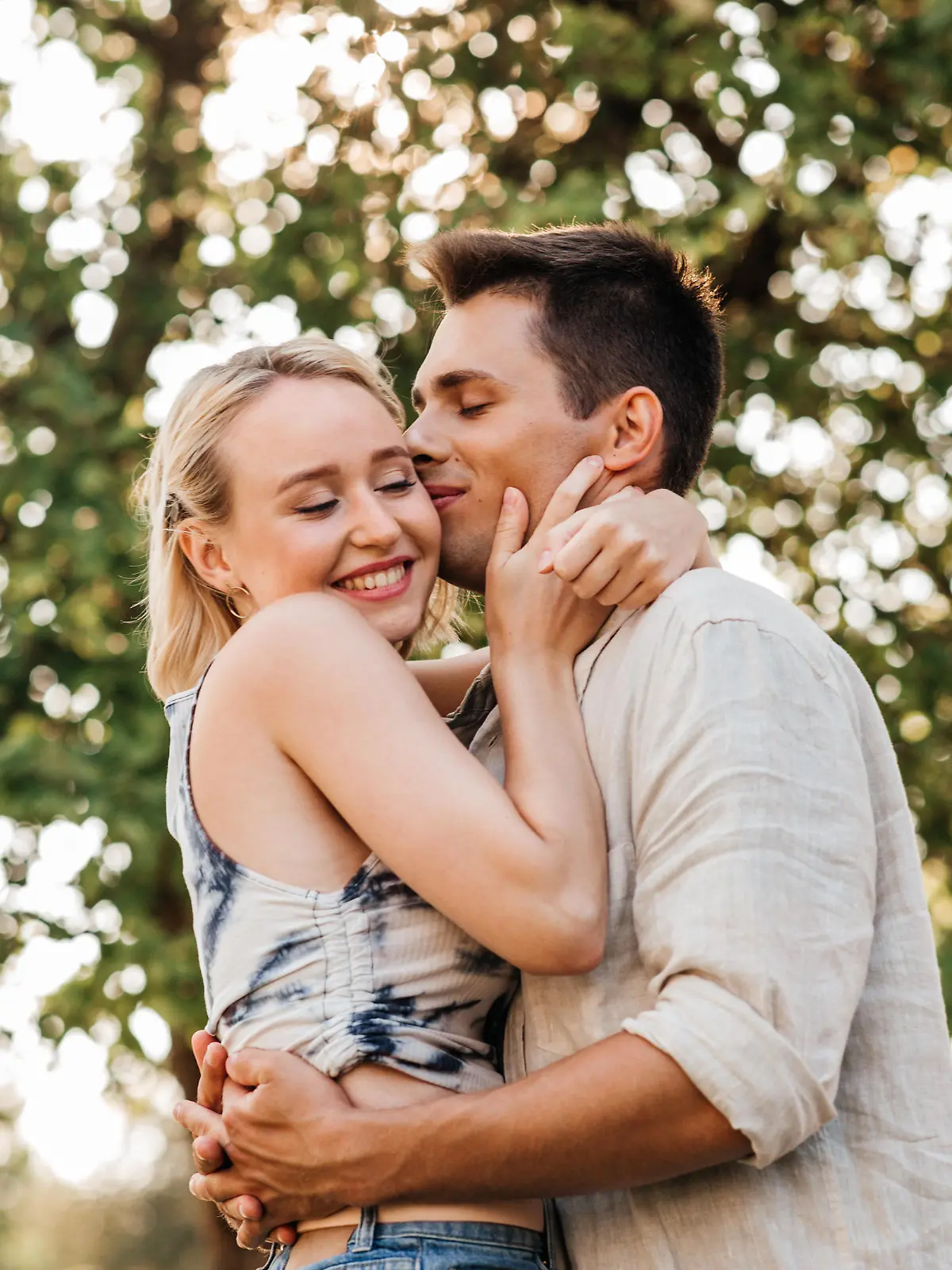 summer holidays, love and people concept - happy young couple kissing and hugging outdoors || Modellfreigabe vorhanden