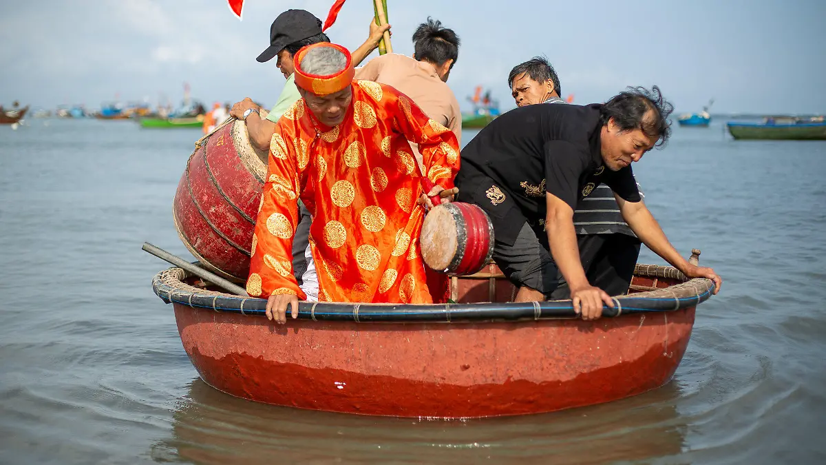 PRODUKTION - 02.03.2021, Vietnam, Tam Hai: In Tam Hai bringen einheimische Fischer während des örtlichen Walanbetungsfestes einen älteren Walanbeter in einem Kahn zu einem Tempelboot.    (zu dpa: «Schutz aus den Tiefen des Ozeans: Die Wal-Götter von Vietnam») Foto: Chris Humphrey/dpa +++ dpa-Bildfunk +++