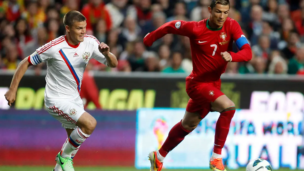 Portugal's Cristiano Ronaldo (R) fights for the ball with Russia's Igor Denisov during their 2014 World Cup qualifying soccer match at Luz stadium in Lisbon June 7, 2013. REUTERS/Jose Manuel Ribeiro (PORTUGAL - Tags: SPORT SOCCER)
