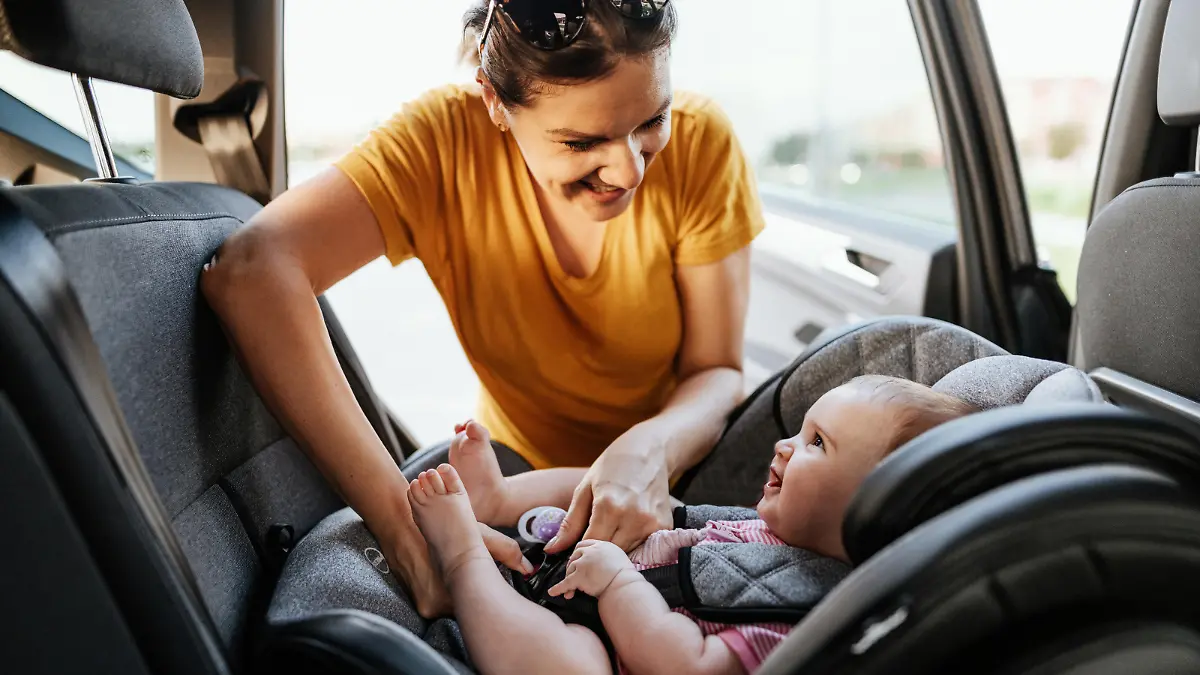 Mother putting baby girl in baby car seat