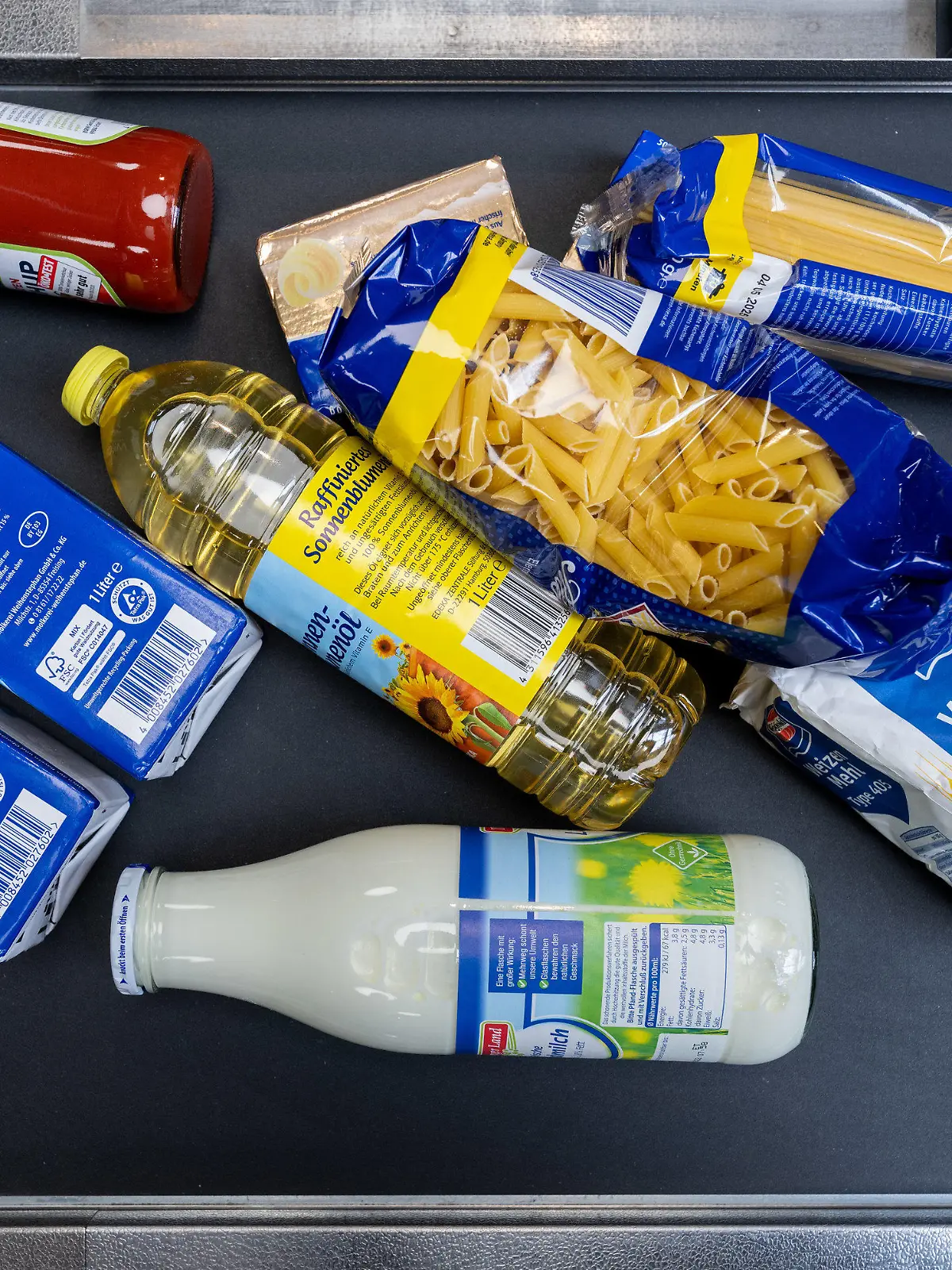 ARCHIV - 02.06.2022, Sachsen, Leipzig: Lebensmittel, darunter Sonnenblumenöl und Getreideprodukte, liegen in einem Supermarkt in Leipzig an der Kasse auf dem Band. Die Auswirkungen des Ukraine-Krieges auf die Agrarmärkte und die Lebensmittelpreise sind zentrale Themen auf dem Deutschen Bauerntag. (Zu dpa "Bauerntag: Folgen des Ukraine-Kriegs und Nahrungspreise im Blick") Foto: Hendrik Schmidt/dpa +++ dpa-Bildfunk +++
