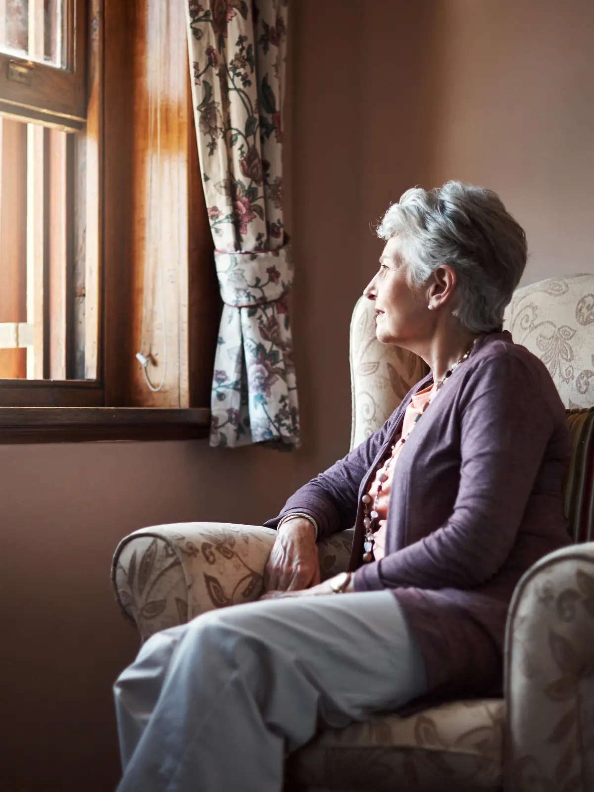 Eine Seniorin schaut aus dem Fenster.