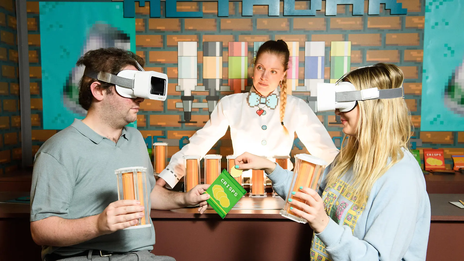 Heineken Silver IRL META-BAR, London. EDITORIAL USE ONLY Guests Brendan Hodrien and Ria Bussey (right) at at the Heineken Silver IRL META-BAR in Shoreditch, London, a spoof 'virtual' bar serving fake beers to patrons wearing pretend actual reality headsets, marking the UK launch of Heineken Silver. Picture date: Thursday April 7, 2022. The spoof 'In Real Life' bar comes as a reaction to the recent trend of food and drink companies opening restaurants and bars in the metaverse. After experiencing a bar that served no drinks, guests were invited to adjoining bar, 'Silverland', where they were able to experience a host of activities 'best enjoyed real', including drinking a pint of Heineken Silver and a DJ set from Snoochie Shy. Photo credit should read: Matt Crossick/PA Wire URN:66272381