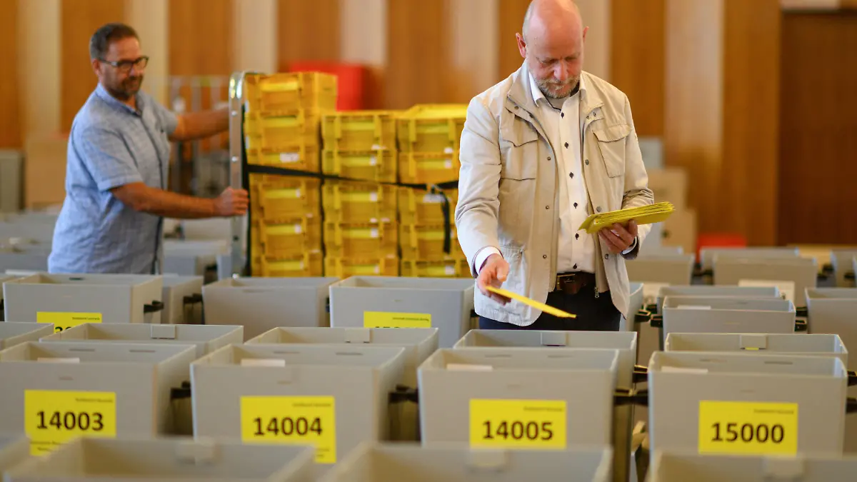 09.06.2022, Sachsen, Dresden: Markus Blocher (r), Kreiswahlleiter, begutachtet während eines Fototermins im Rathaus zahlreiche Sammelbehälter, gefüllt mit Stimmzettelumschlägen für die Briefwahl zur Oberbürgermeisterwahl 2022 in Dresden, im Hintergrund schiebt Sven Mania, städtischen Projektleiter, einen Wagen mit weiteren Umschlägen vorbei. Insgesamt sind etwa 434 000 Bürgerinnen und Bürger am 12. Juni 2022 wahlberechtigt. Foto: Robert Michael/dpa +++ dpa-Bildfunk +++