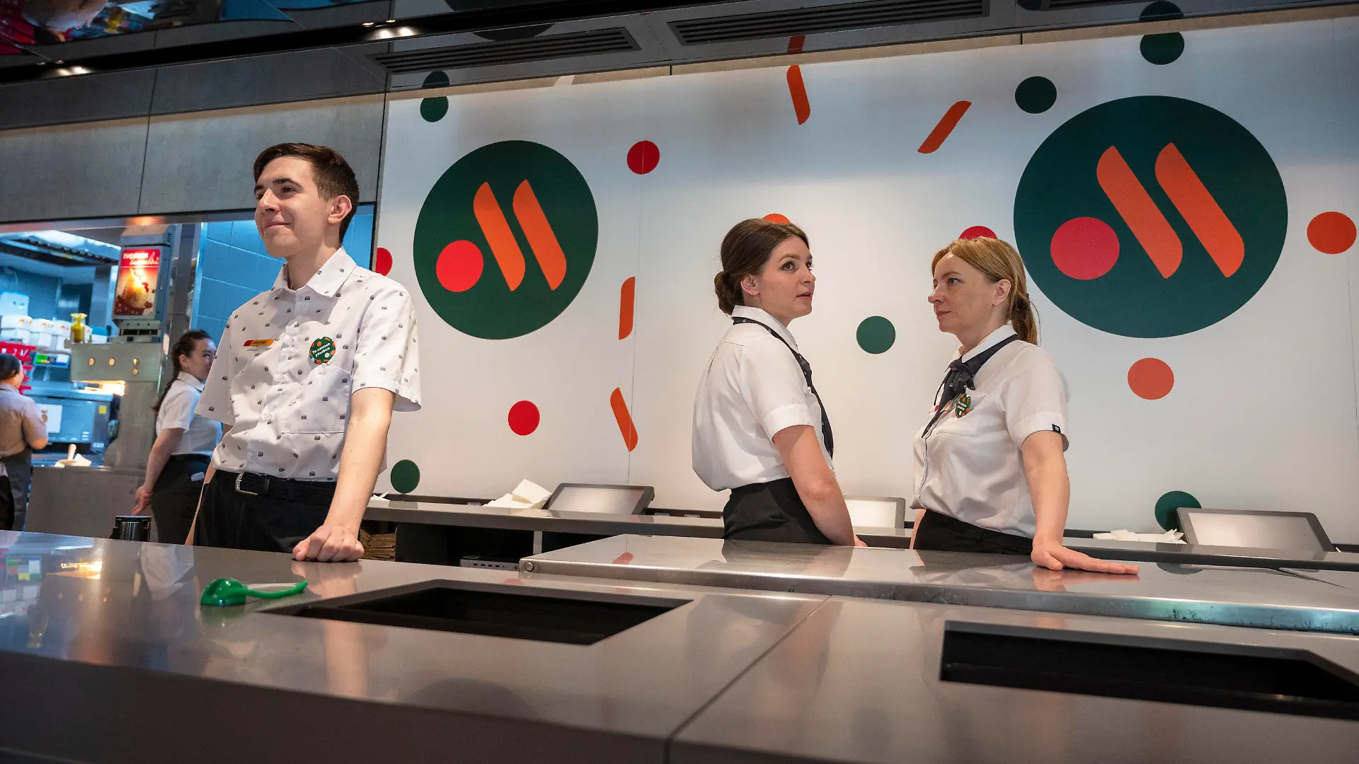 dpatopbilder - 12.06.2022, Russland, Moskau: Mitarbeiterinnen und Mitarbeiter warten in einem neu eröffneten Fast-Food-Restaurant einer ehemaligen McDonald's Filiale auf Kunden. Die Kette trägt jetzt den Namen «Wkusno i totschka»: «Lecker und Punkt». Sie hat auch ein neues Logo: Zwei orange Striche und ein roter Kreis auf dunkelgrünem Hintergrund, es soll zwei Fritten und ein Burgerpatty darstellen. Nachdem McDonald's als Reaktion auf Russlands Angriffskrieg in der Ukraine alle Filialen im Land schloss, eröffnen Filialen wieder unter einem neuen, russischen Besitzer. Insgesamt 15 Filialen in Moskau und Umgebung sollen an diesem Sonntag wieder Gäste empfangen - unter neuem Namen und Logo, aber an denselben Standorten, mit demselben Personal und fast identischen Gerichten. Foto: Dmitry Serebryakov/AP/dpa +++ dpa-Bildfunk +++