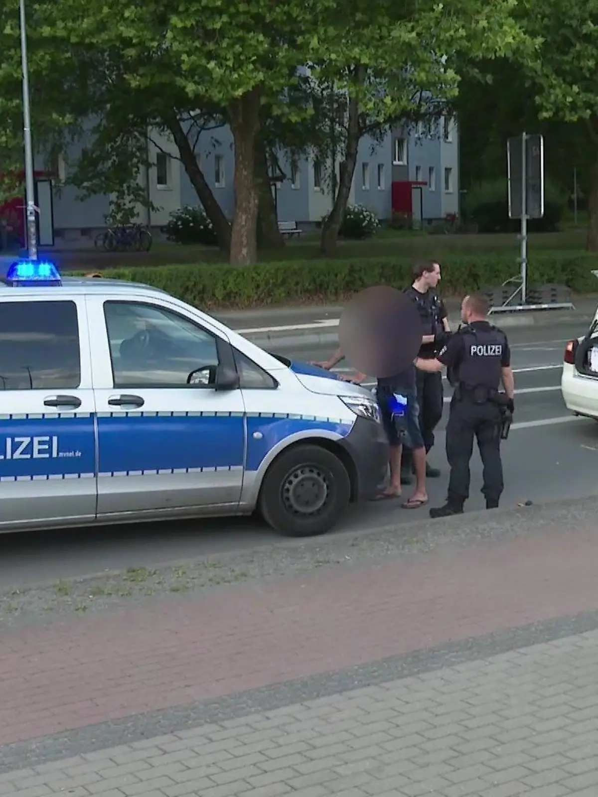 Festnahme: Einer der Tatverdächtigen wird von der Polizei festgehalten, während die mutmaßlich attackierte Frau eine Aussage macht.