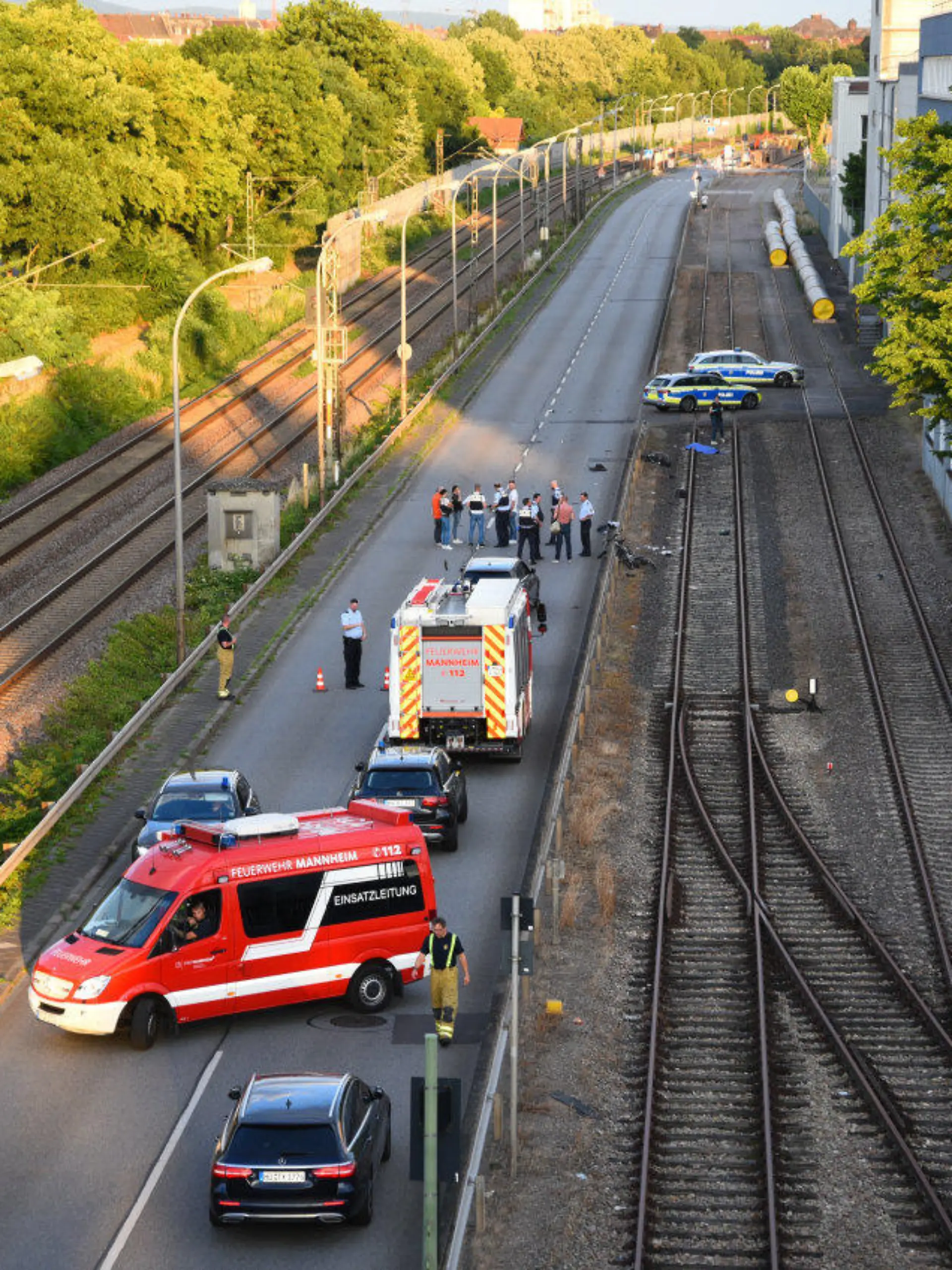 12.06.2022, Baden-Württemberg, Mannheim: Rettungskräfte und Polizei sind an einem Tatort auf der Rhenaniastraße im Einsatz. Ein flüchtiger Mann, der zuvor seinen Vater getötet haben soll, hat in Mannheim vier Fahrradfahrer mit einem Auto angefahren. Eine 71-jährige Radfahrerin wurde dabei tödlich verletzt. Drei weitere Menschen wurden schwer verletzt und kamen in Krankenhäuser, wie Polizei und Staatsanwaltschaft am Sonntagabend berichteten. «Durch Polizeikräfte konnte der Mann, welcher sich vermutlich in einem psychischen Ausnahmezustand befand, schließlich festgenommen werden», berichteten die Ermittler. Foto: René Priebe/PR-Video/dpa +++ dpa-Bildfunk +++