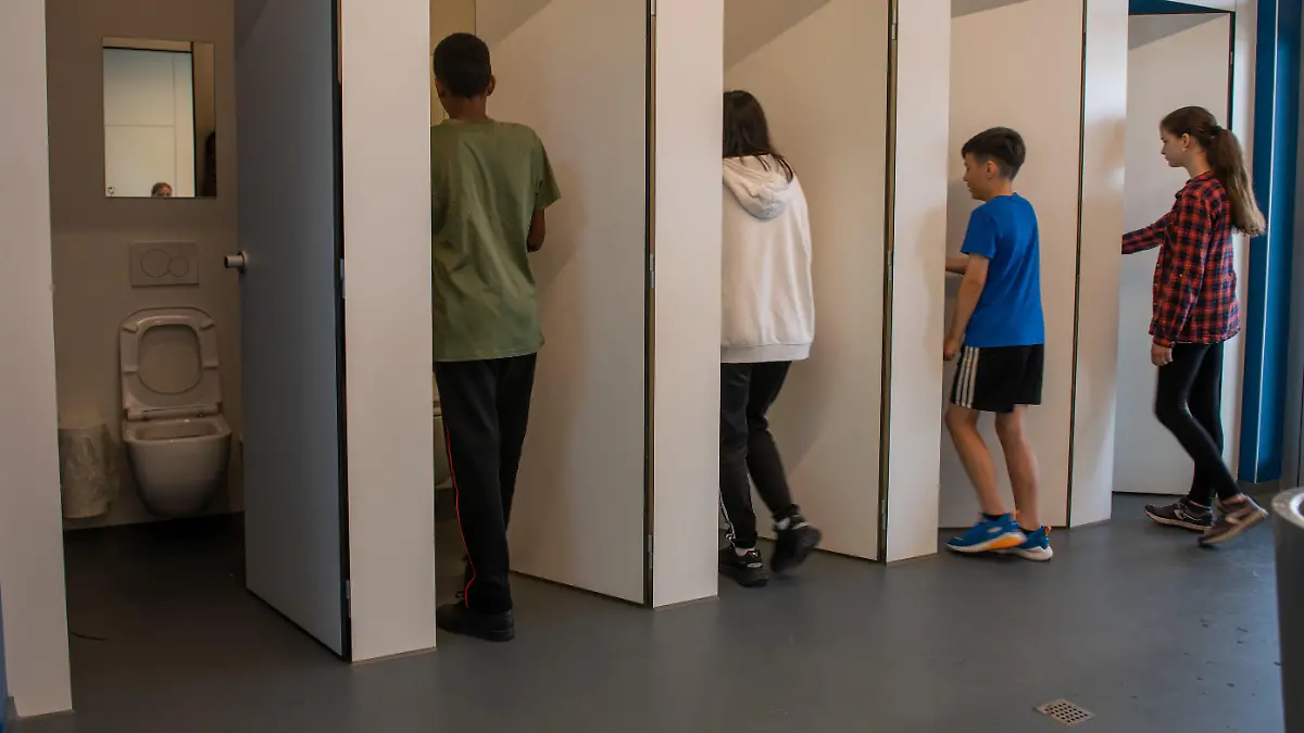 03.06.2022, Baden-Württemberg, Ulm: Jungen und Mädchen gehen in eine Unisextoilette an der Sägefeldschule im Ortsteil Wiblingen. Bei der Sanierung der Toilettenanlage an der Werkrealschule wurde die Geschlechtertrennung aufgehoben. Foto: Stefan Puchner/dpa +++ dpa-Bildfunk +++