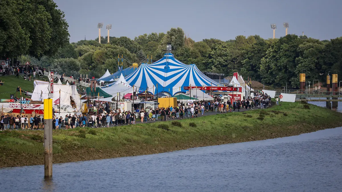 PRODUKTION - 12.07.2023, Bremen: Festivalbesucher gehen am Eröffnungsabend der Breminale am Osterdeich an der Weser in Bremen über das Veranstaltungsgelände. Das Bremer Umsonst-und-draußen-Festival hofft bei seiner Neuauflage vom 12. bis 16. Juli auf etwa 200 000 Besucherinnen und Besucher. Foto: Focke Strangmann/dpa +++ dpa-Bildfunk +++