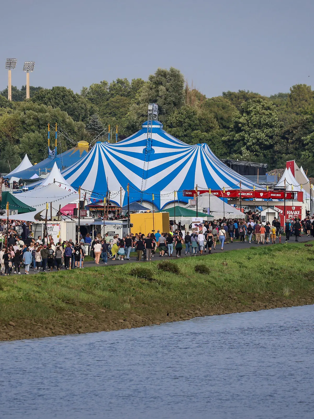 PRODUKTION - 12.07.2023, Bremen: Festivalbesucher gehen am Eröffnungsabend der Breminale am Osterdeich an der Weser in Bremen über das Veranstaltungsgelände. Das Bremer Umsonst-und-draußen-Festival hofft bei seiner Neuauflage vom 12. bis 16. Juli auf etwa 200 000 Besucherinnen und Besucher. Foto: Focke Strangmann/dpa +++ dpa-Bildfunk +++