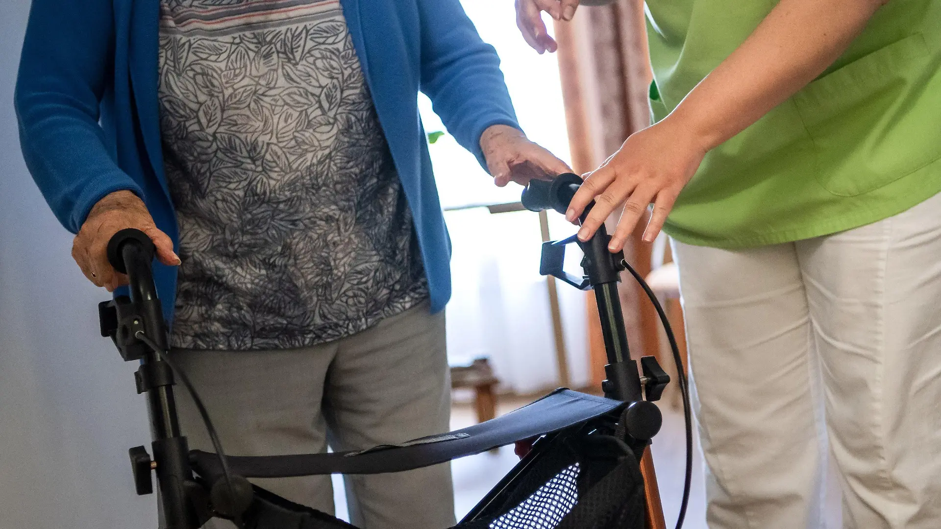 ARCHIV - 16.06.2021, Niedersachsen, Nienburg: Eine Pflegefachkraft hilft einer Bewohnerin in einem Seniorenheim mit ihrem Rollator. Für Bewohnerinnen und Bewohner in Pflegeheimen sind selbst zu zahlende Anteile noch weiter gestiegen.(zu dpa "Zuzahlungen für Pflege im Heim noch weiter gestiegen ") Foto: Sina Schuldt/dpa +++ dpa-Bildfunk +++