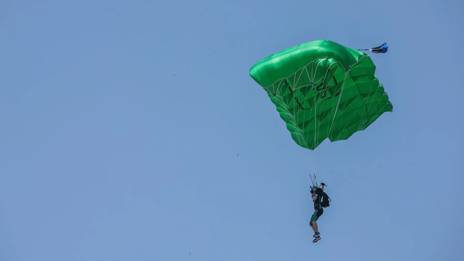 Ein Fallschirmspringer fliegt langsam auf die Erde.