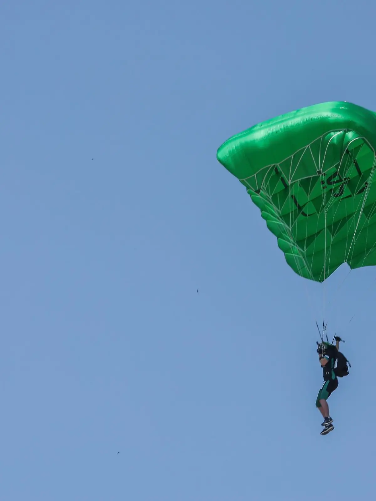 Ein Fallschirmspringer fliegt langsam auf die Erde.