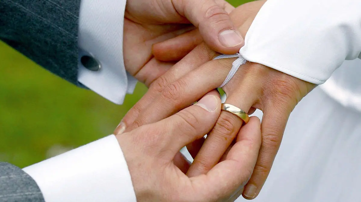 ARCHIV - 26.04.2003, Sachsen-Anhalt, Magdeburg: Bei der Trauung streift der Bräutigam der Braut einen Ehering über den Ringfinger. Heiratstermine an Schnapszahltagen sind beliebt. (zu dpa «Heiraten am Schnapszahldatum - Standesämter haben gut zu tun») Foto: Andreas Lander/zb/dpa +++ dpa-Bildfunk +++