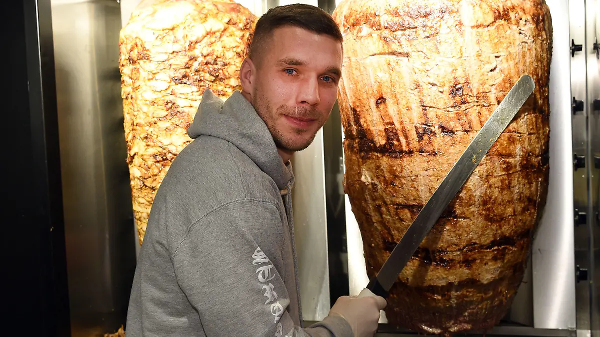 dpatopbilder - Fußball-Weltmeister Lukas Podolski steht am 06.01.2018 in Köln (Nordrhein-Westfalen) bei der Eröffnung eines Döner-Ladens an einem Dönerspieß. Podolski ist Mitgesellschafter bei «Mangal Döner» Foto: Henning Kaiser/dpa +++(c) dpa - Bildfunk+++