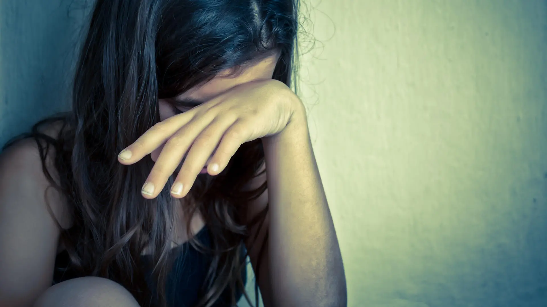 Sad and lonely girl crying with a hand covering her face (with space for text)