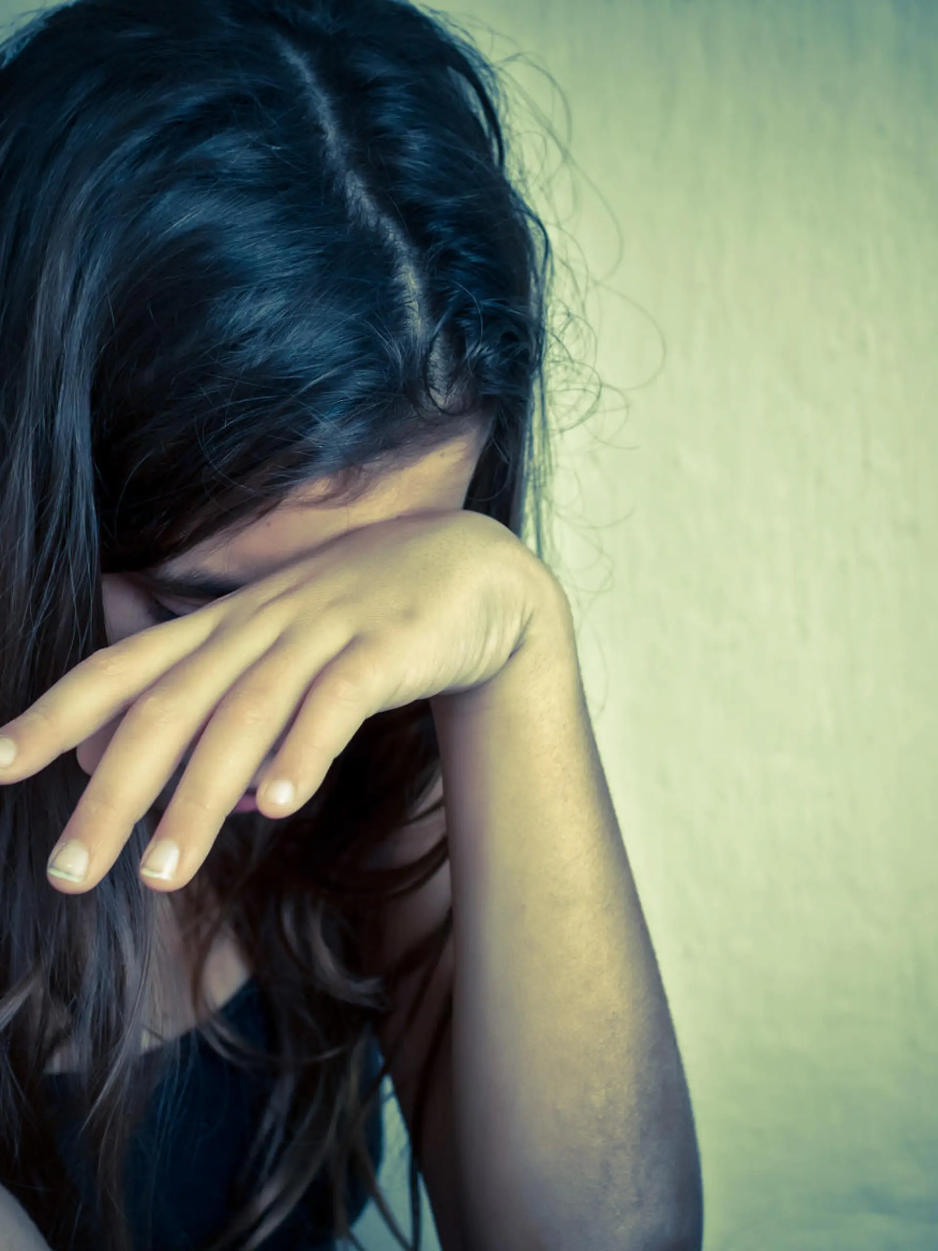 Sad and lonely girl crying with a hand covering her face (with space for text)