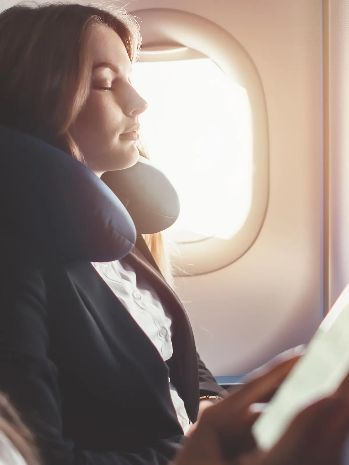 Two females going on business trip by plane. A woman reading an e-book on a smartphone.