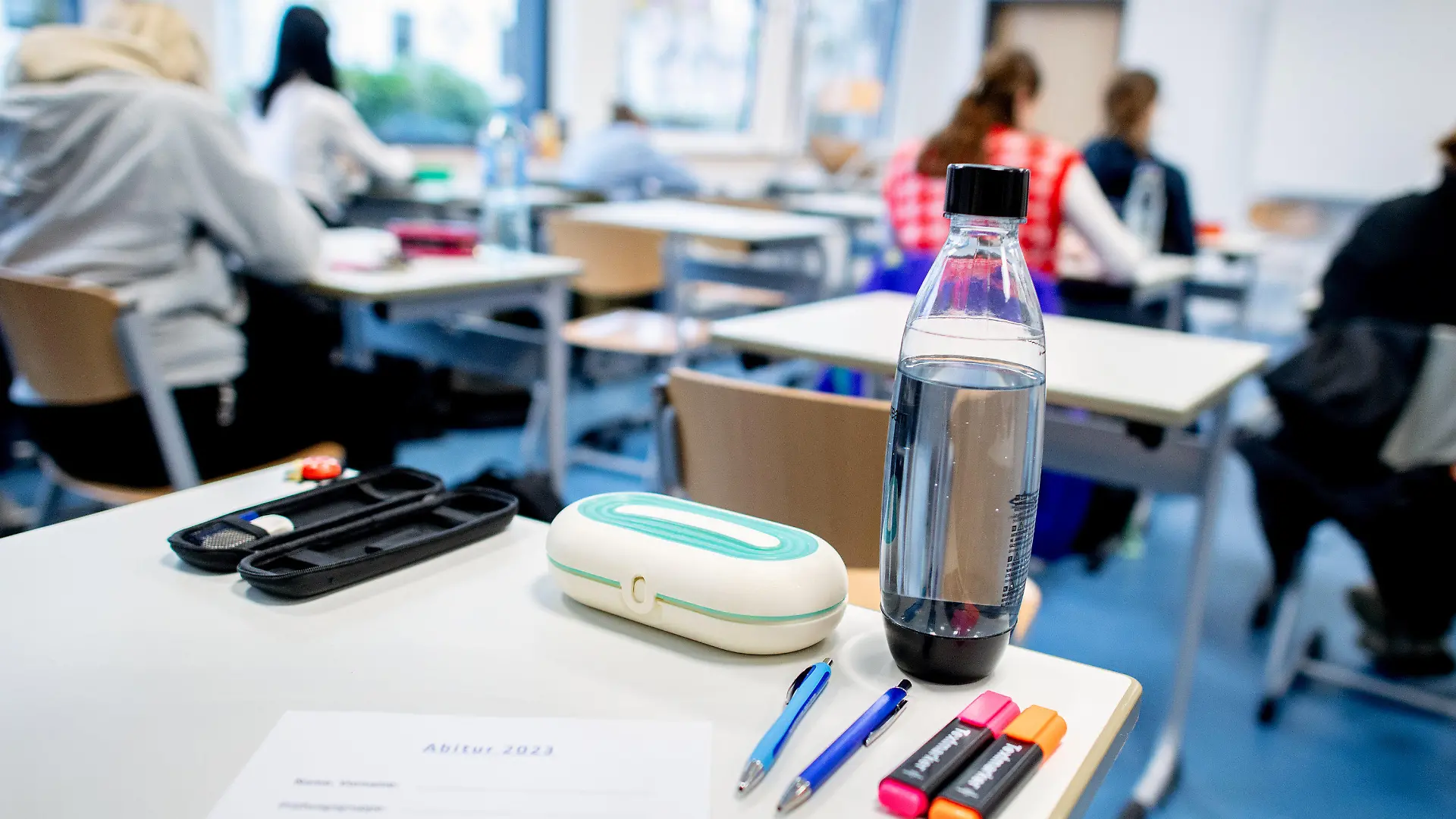 17.04.2023, Niedersachsen, Oldenburg: Mehrere Stifte liegen und eine Wasserflasche steht vor Beginn der schriftlichen Abiturprüfungen im Fach Geschichte auf einem Tisch in der Graf-Anton-Günther-Schule (GAG). In Niedersachsen beginnen die Abschlussprüfungen für den Abiturjahrgang 2023. Bis zum 09.05.2023 werden die Klausuren in unterschiedlichen Fächern geschrieben. Foto: Hauke-Christian Dittrich/dpa +++ dpa-Bildfunk +++