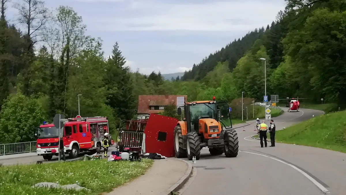 Rettungskräfte stehen nach einem Unfall neben einem einem umgestürzten Maiwagen. Bei dem Unfall mit einem Maiwagen-Anhänger sind im südbadischen Kandern rund dreißig Menschen verletzt worden. Zehn Menschen hätten schwere Verletzungen erlitten, teilte die Polizei am Mittwoch mit.