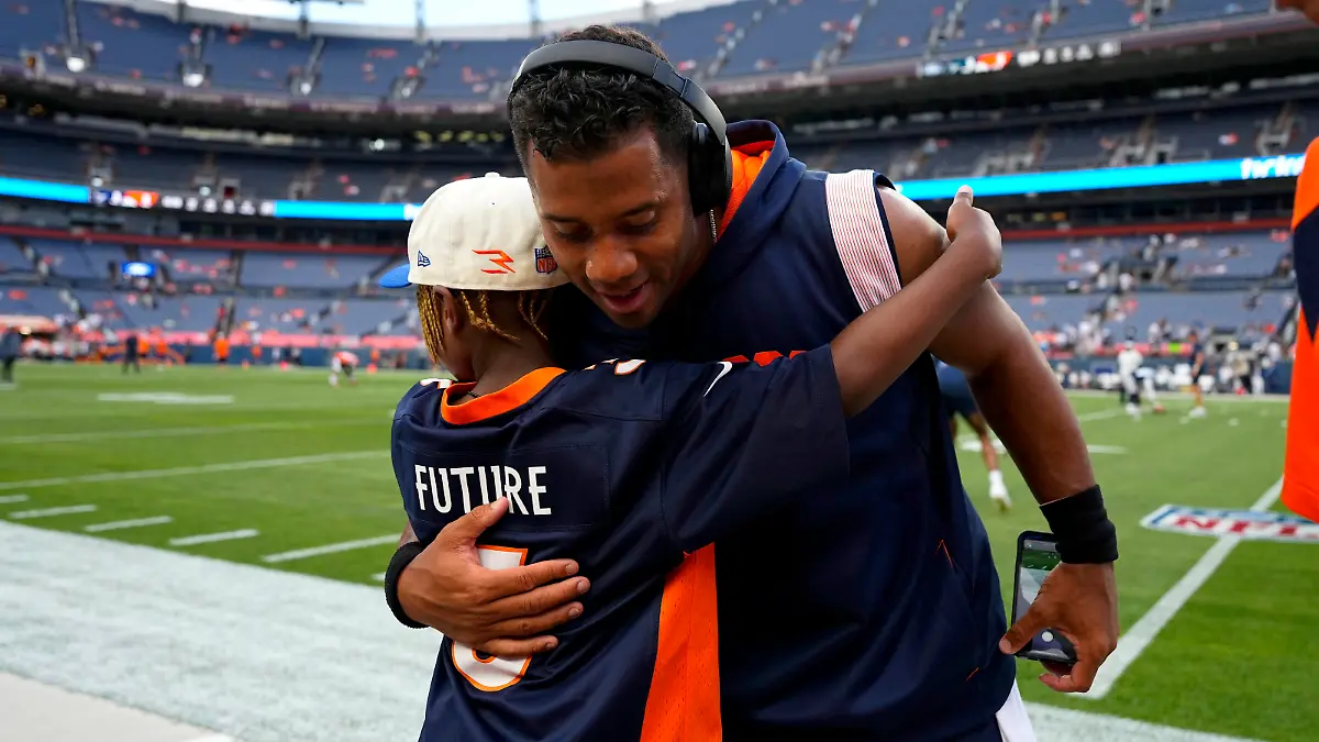 Denver Broncos quarterback Russell Wilson hugs his son, Future, prior to an NFL preseason football game against the Dallas Cowboys, Saturday, Aug. 13, 2022, in Denver. (AP Photo/Jack Dempsey)