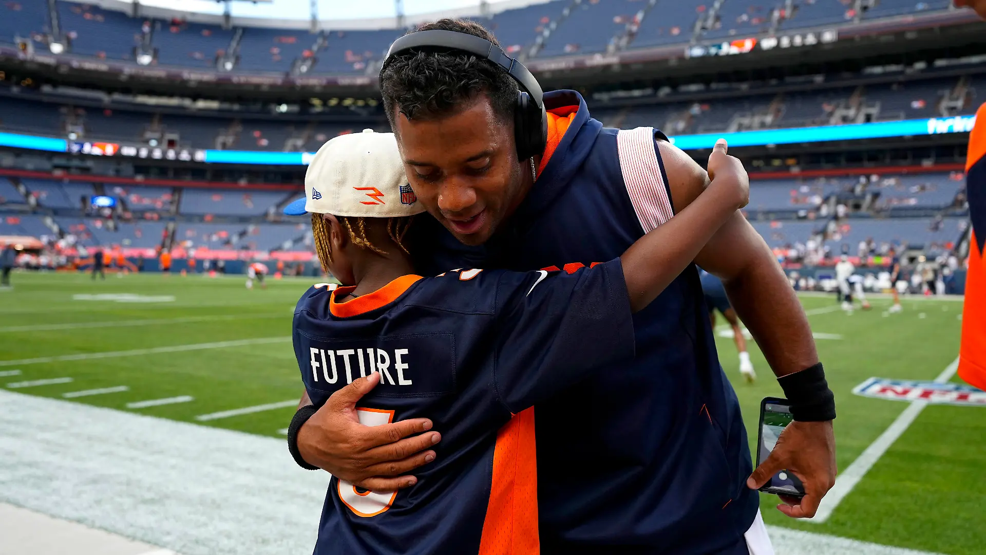 Denver Broncos quarterback Russell Wilson hugs his son, Future, prior to an NFL preseason football game against the Dallas Cowboys, Saturday, Aug. 13, 2022, in Denver. (AP Photo/Jack Dempsey)