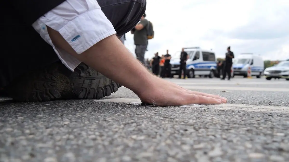 14.07.2023, Bremen: Ein Klimaaktivist hat sich mit der Handfläche am Asphalt einer Straße in der Bremer Innenstadt festgeklebt. In Bremen blockierten gegen 11.30 Uhr den Polizeiangaben nach sieben Aktivisten eine Straße an der Kreuzung Altenwall und Tiefer. Vier Menschen klebten sich auf der Straße fest. Der Verkehr wurde umgeleitet. Es kam der Polizei zufolge zu keinen großen Behinderungen. Polizisten lösten die Aktivisten vom Asphalt und stellten die Personalien aller Blockierer fest. Foto: Jörn Hünecke/dpa +++ dpa-Bildfunk +++