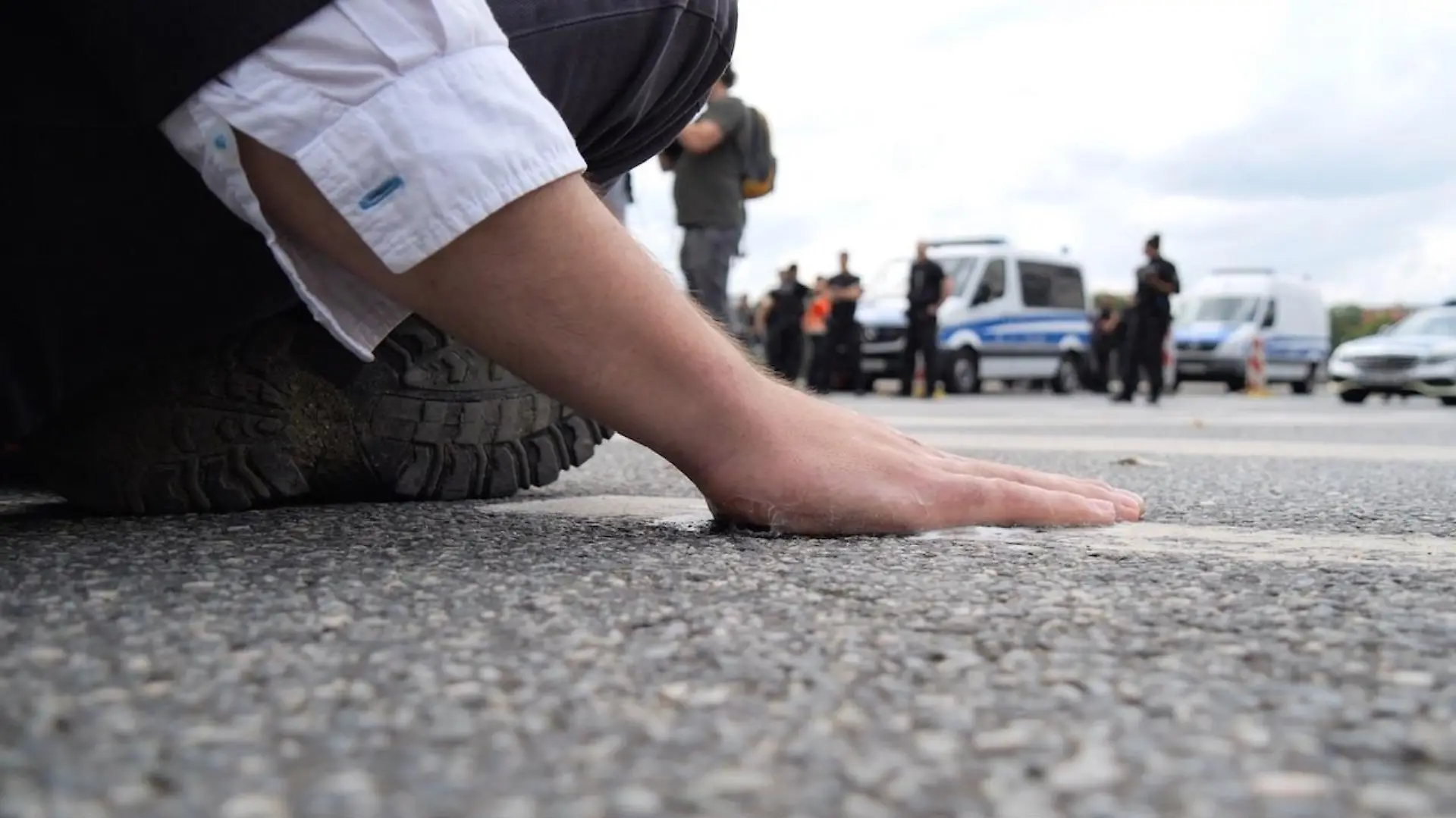 14.07.2023, Bremen: Ein Klimaaktivist hat sich mit der Handfläche am Asphalt einer Straße in der Bremer Innenstadt festgeklebt. In Bremen blockierten gegen 11.30 Uhr den Polizeiangaben nach sieben Aktivisten eine Straße an der Kreuzung Altenwall und Tiefer. Vier Menschen klebten sich auf der Straße fest. Der Verkehr wurde umgeleitet. Es kam der Polizei zufolge zu keinen großen Behinderungen. Polizisten lösten die Aktivisten vom Asphalt und stellten die Personalien aller Blockierer fest. Foto: Jörn Hünecke/dpa +++ dpa-Bildfunk +++
