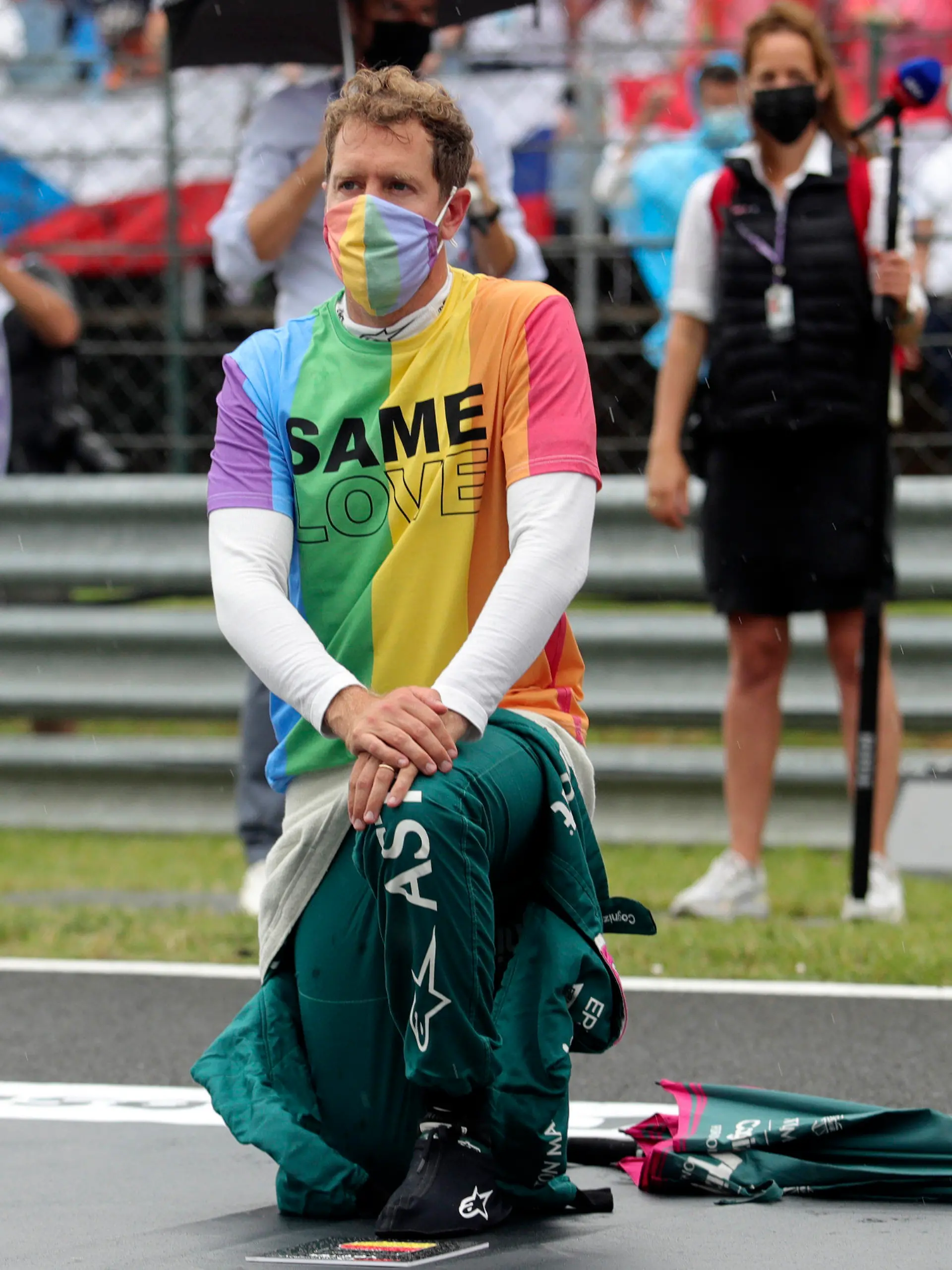 ARCHIV - 01.08.2021, Ungarn, Mogyorod: Motorsport: Formel-1-Weltmeisterschaft, Großer Preis von Ungarn, Rennen: Sebastian Vettel aus Deutschland vom Team Aston-Martin kniet vor dem Rennen auf der Rennstrecke zur Unterstützung der Black-Lives-Matter-Bewegung nieder und trägt eine T-Shirt in Regenbogenfarben. (zu dpa ««Heuchler» Vettel: Vom Weltmeister zum Weltverbesserer») Foto: Florion Goga/Pool Reuters/AP/dpa +++ dpa-Bildfunk +++