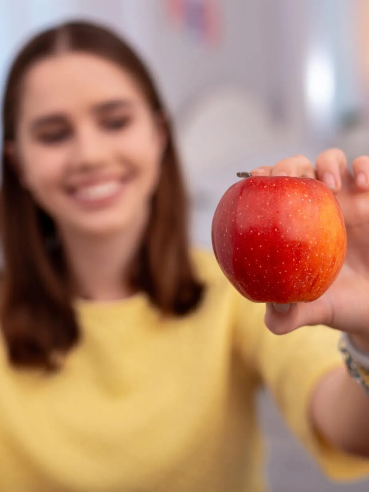 Juicy apple. Selective focus of fresh red apple hold by teen girl who smiling