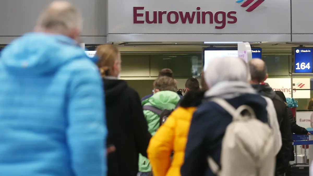 14.03.2021, Nordrhein-Westfalen, Düsseldorf: Passagiere stehen am Flughafen Düsseldorf in einer Schlange, um für einen Eurowings-Flug nach Palma de Mallorca einzuchecken. Wegen stark sinkender Corona-Infektionszahlen gelten Mallorca, die anderen Balearen-Inseln sowie Teile des spanischen Festlands nach einer Entscheidung der Bundesregierung von diesem Sonntag an nicht mehr als Risikogebiet. Urlaub in diesen Reisezielen ist wieder ohne Quarantäne und Testpflicht nach der Rückkehr möglich. Foto: David Young/dpa +++ dpa-Bildfunk +++