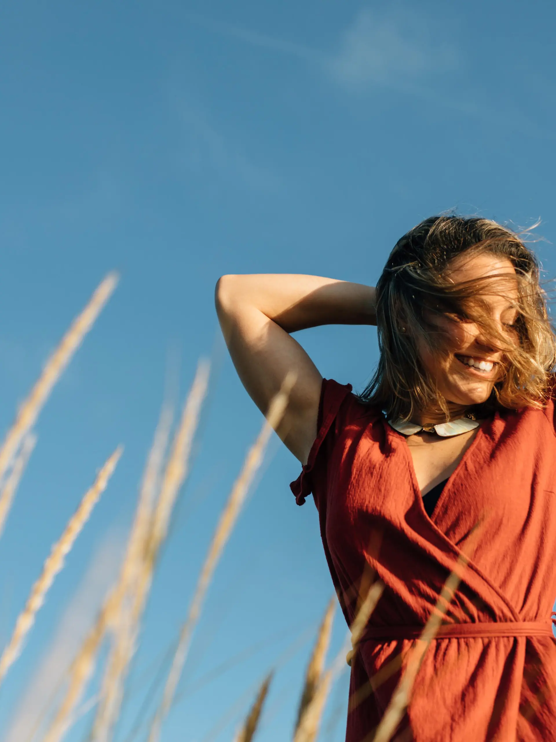 Summer freedom and relaxing leisure. Young happy woman raising arms to feel the breeze at the beach.