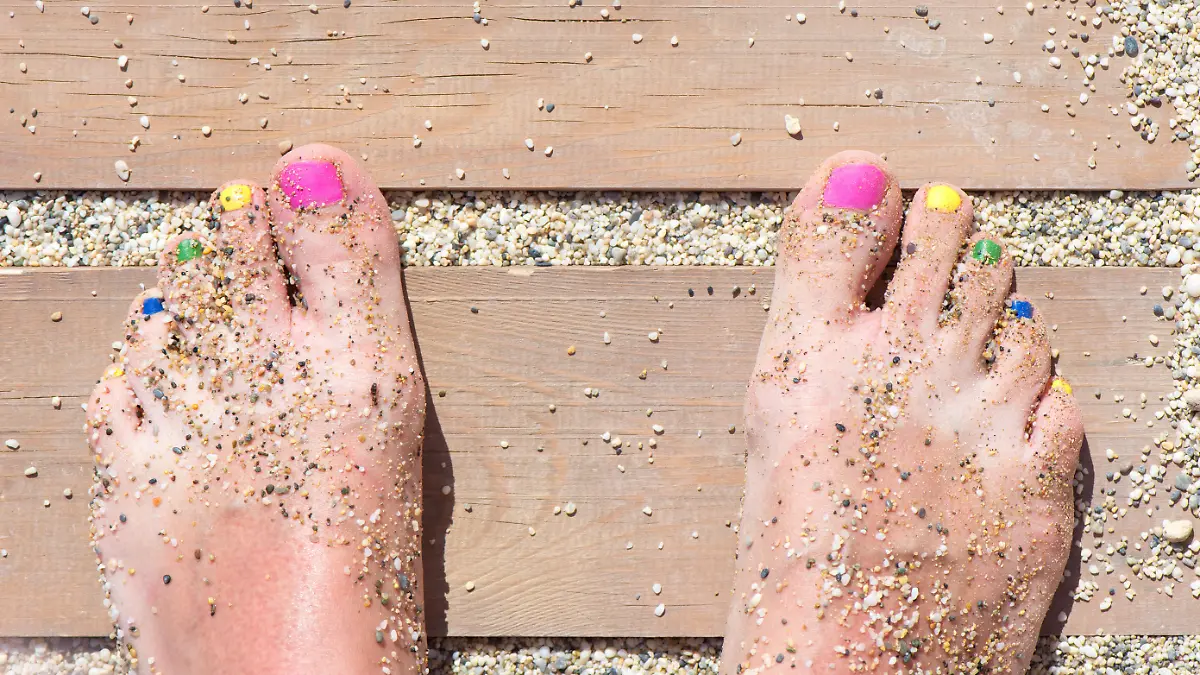 Colorful women feet nails on the beach
