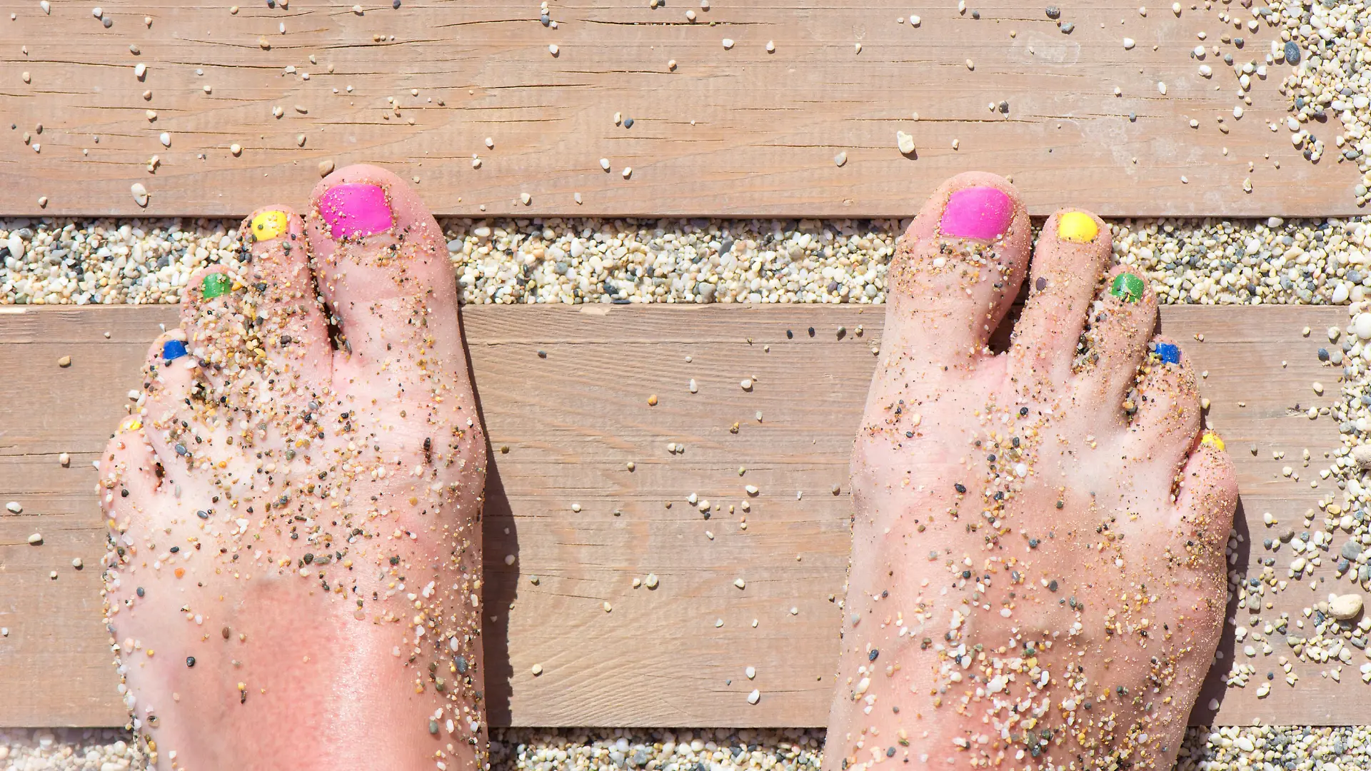 Colorful women feet nails on the beach