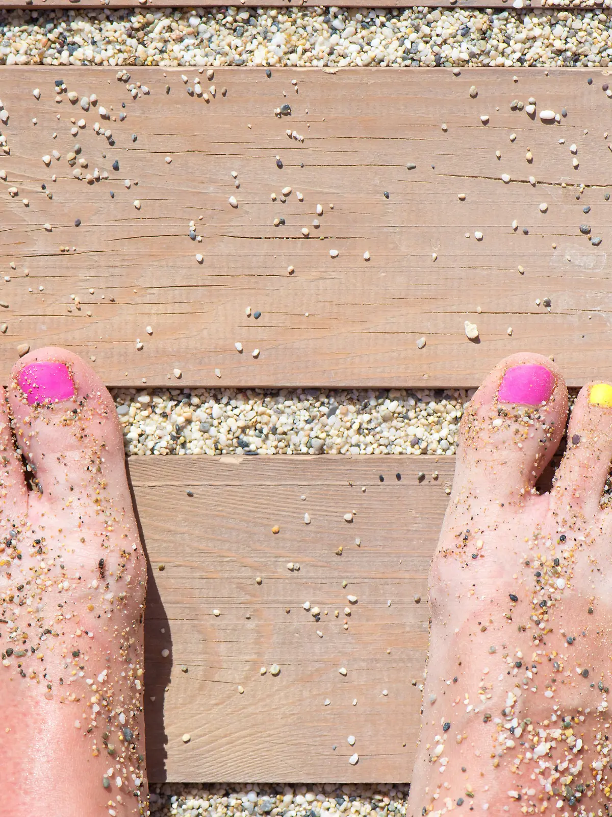 Colorful women feet nails on the beach