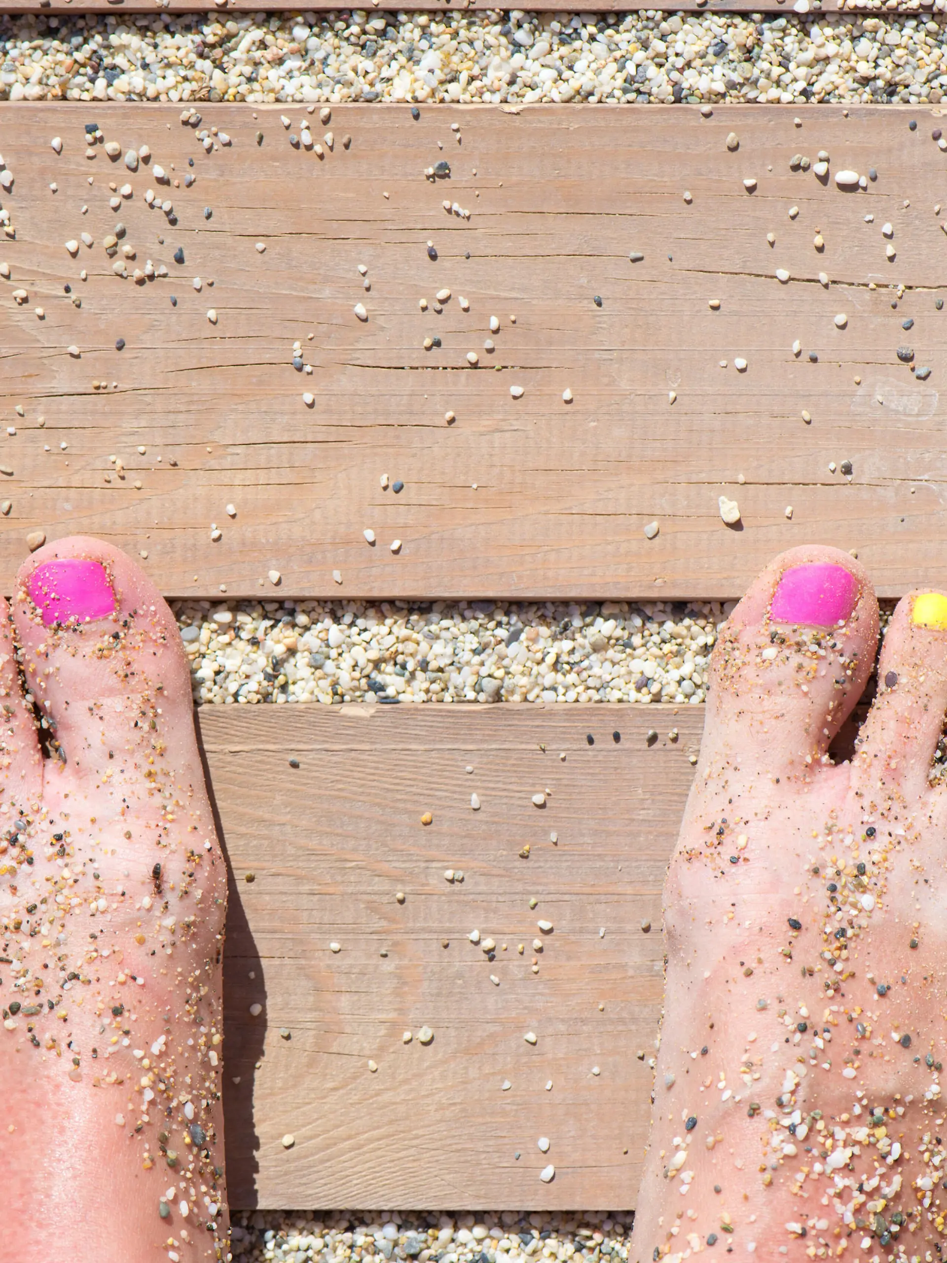 Colorful women feet nails on the beach