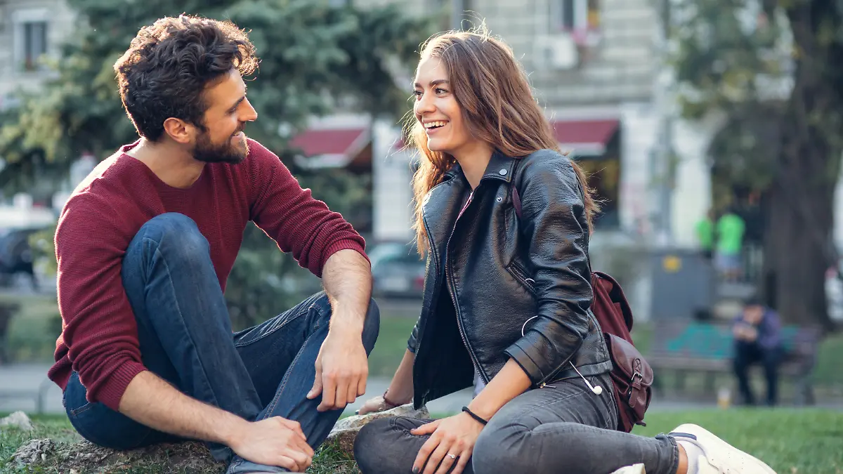 Happy couple talking while sitting on a meadow
