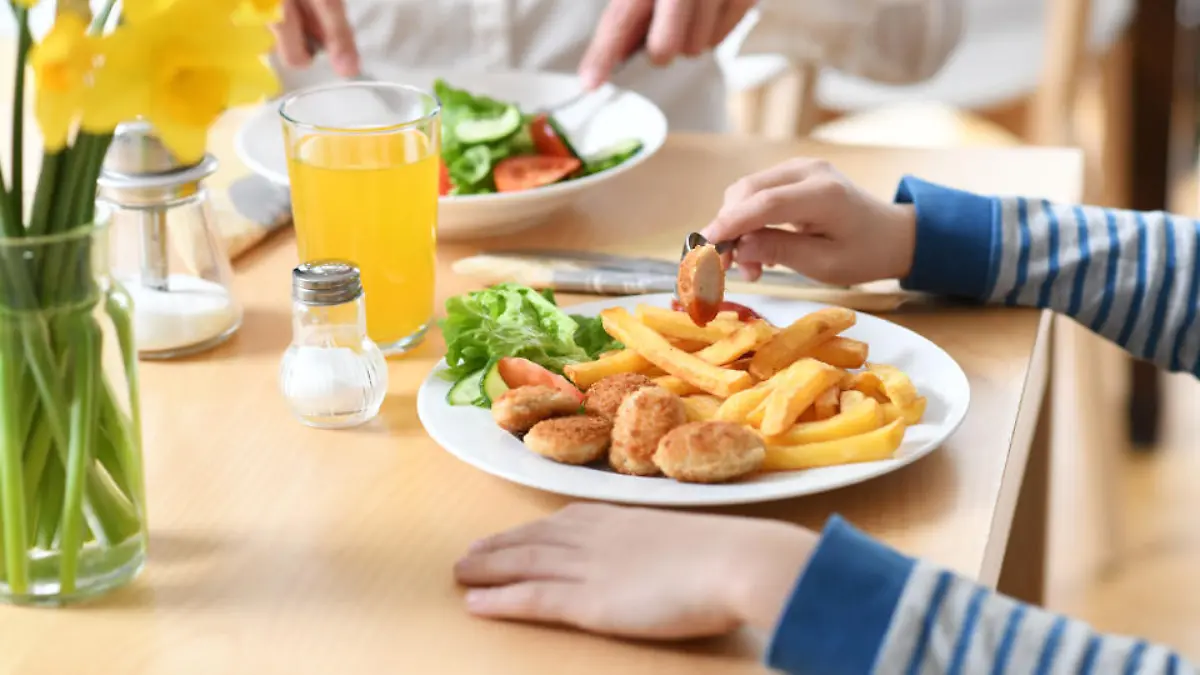19.03.2019, Bayern, München: ILLUSTRATION: Ein Junge sitzt vor einem Teller mit Chicken Nuggets und Pommes Frites (gestellte Szene). Kleines Schnitzel mit Pommes, Fischstäbchen oder Spaghetti - für Kinder gibt es in Restaurants oft nicht nur kleinere Portionen, sondern auch nicht besonders gesunde Gerichte. Foto: Tobias Hase/dpa