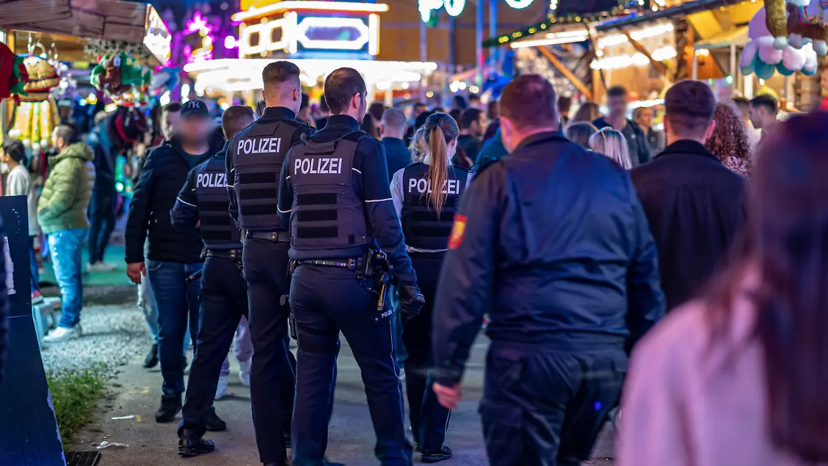 22.05.2022, Nordrhein-Westfalen, Lüdenscheid: Polizeibeamte gehen über das Kirmesgelände Hohen Steinert. Im Rahmen der Kirmes in Lüdenscheid im Nordwesten des Sauerlandes ist ein 40-Jähriger durch einen Schuss getötet worden. Der Mann sei am Samstagabend am Ausgang des Festgeländes von dem Projektil getroffen worden und wenig später in einem Krankenhaus an seinen schweren Verletzungen gestorben. (zu dpa: Mann bei Kirmes erschossen - Gruppe flieht nach Streit) Foto: Markus Klümper/dpa - ACHTUNG: Person(en) wurde(n) aus rechtlichen Gründen gepixelt +++ dpa-Bildfunk +++