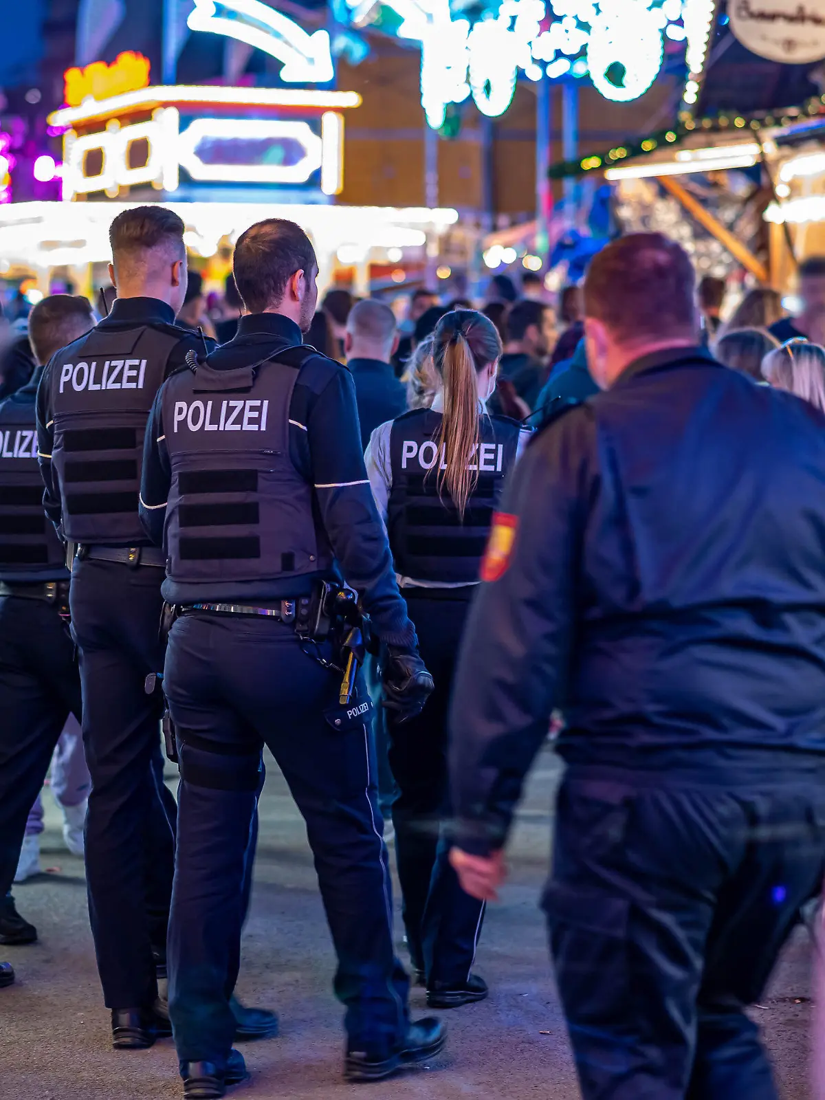 22.05.2022, Nordrhein-Westfalen, Lüdenscheid: Polizeibeamte gehen über das Kirmesgelände Hohen Steinert. Im Rahmen der Kirmes in Lüdenscheid im Nordwesten des Sauerlandes ist ein 40-Jähriger durch einen Schuss getötet worden. Der Mann sei am Samstagabend am Ausgang des Festgeländes von dem Projektil getroffen worden und wenig später in einem Krankenhaus an seinen schweren Verletzungen gestorben. (zu dpa: Mann bei Kirmes erschossen - Gruppe flieht nach Streit) Foto: Markus Klümper/dpa - ACHTUNG: Person(en) wurde(n) aus rechtlichen Gründen gepixelt +++ dpa-Bildfunk +++