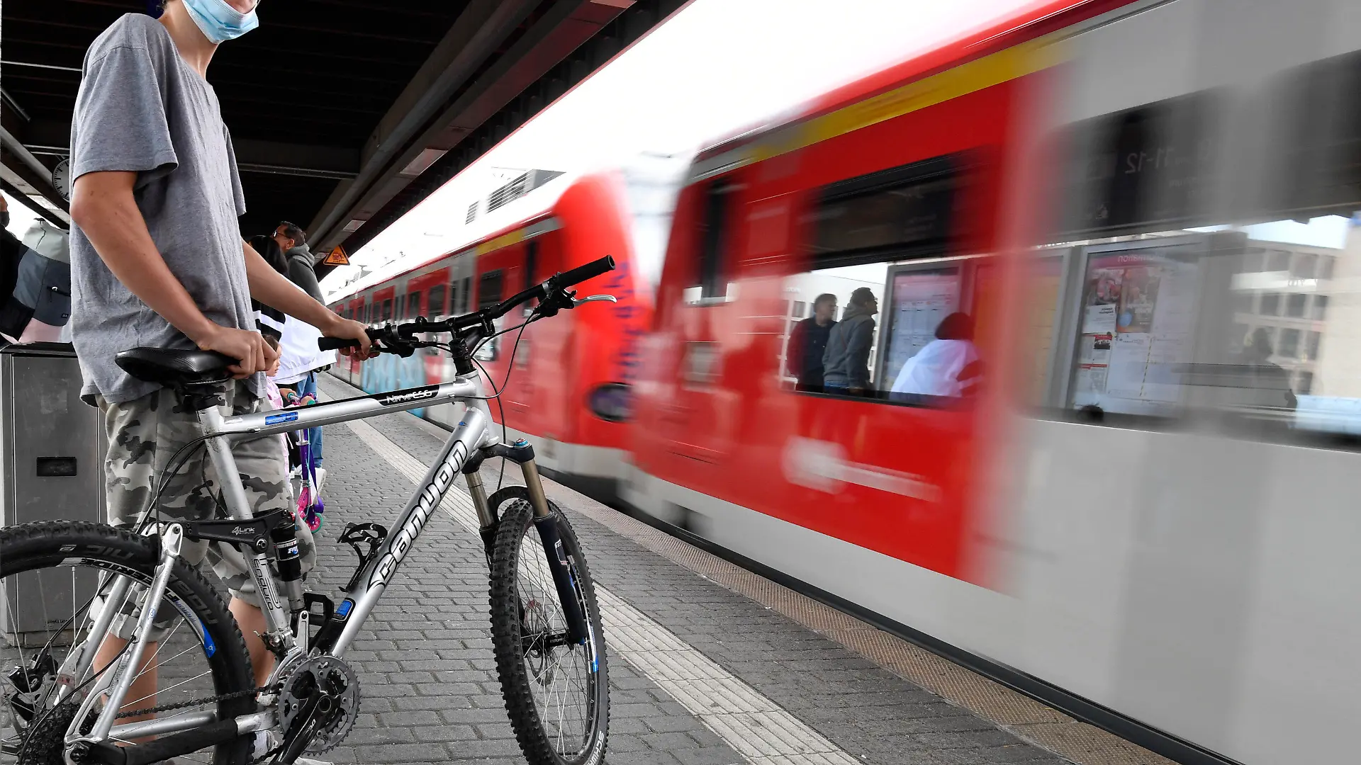 05.06.2022, Nordrhein-Westfalen, Köln: Ein Radfahrer wartet auf die Einfahrt eines Regionalzuges am Deuter Bahnhof. Durch das 9-Euro-Ticket verzeichnet die Deutsche Bahn mehr ausgelastete Züge an Pfingsten. Foto: Roberto Pfeil/dpa +++ dpa-Bildfunk +++