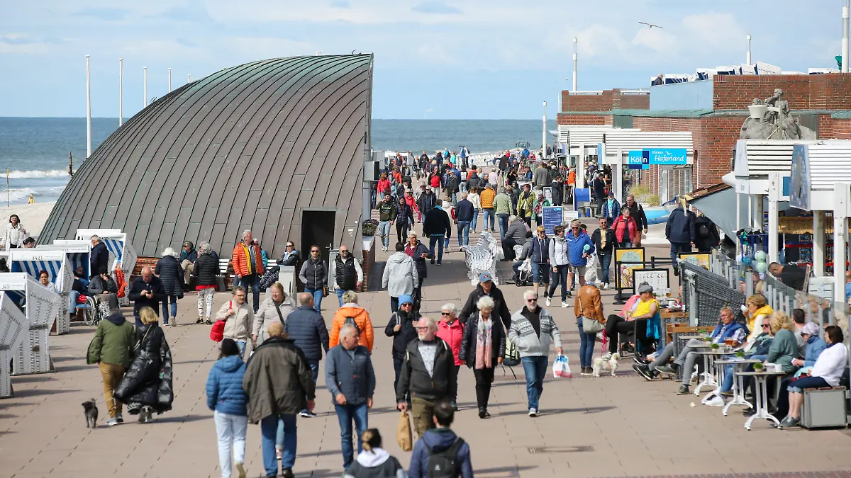 PRODUKTION - 30.05.2022, Schleswig-Holstein, Westerland: Besucher sind auf der Kurpromenade von Westerland bei der "Musikmuschel" unterwegs. Mit dem Start des 9-Euro-Tickets ab dem 1. Juni 2022 werden auch mehr Besucher auf der Insel erwartet. (zu dpa: «Pfingsten - Sylt bereitet sich auf zusätzliche Besucher vor») Foto: Bodo Marks/Bodo Marks/dpa +++ dpa-Bildfunk +++