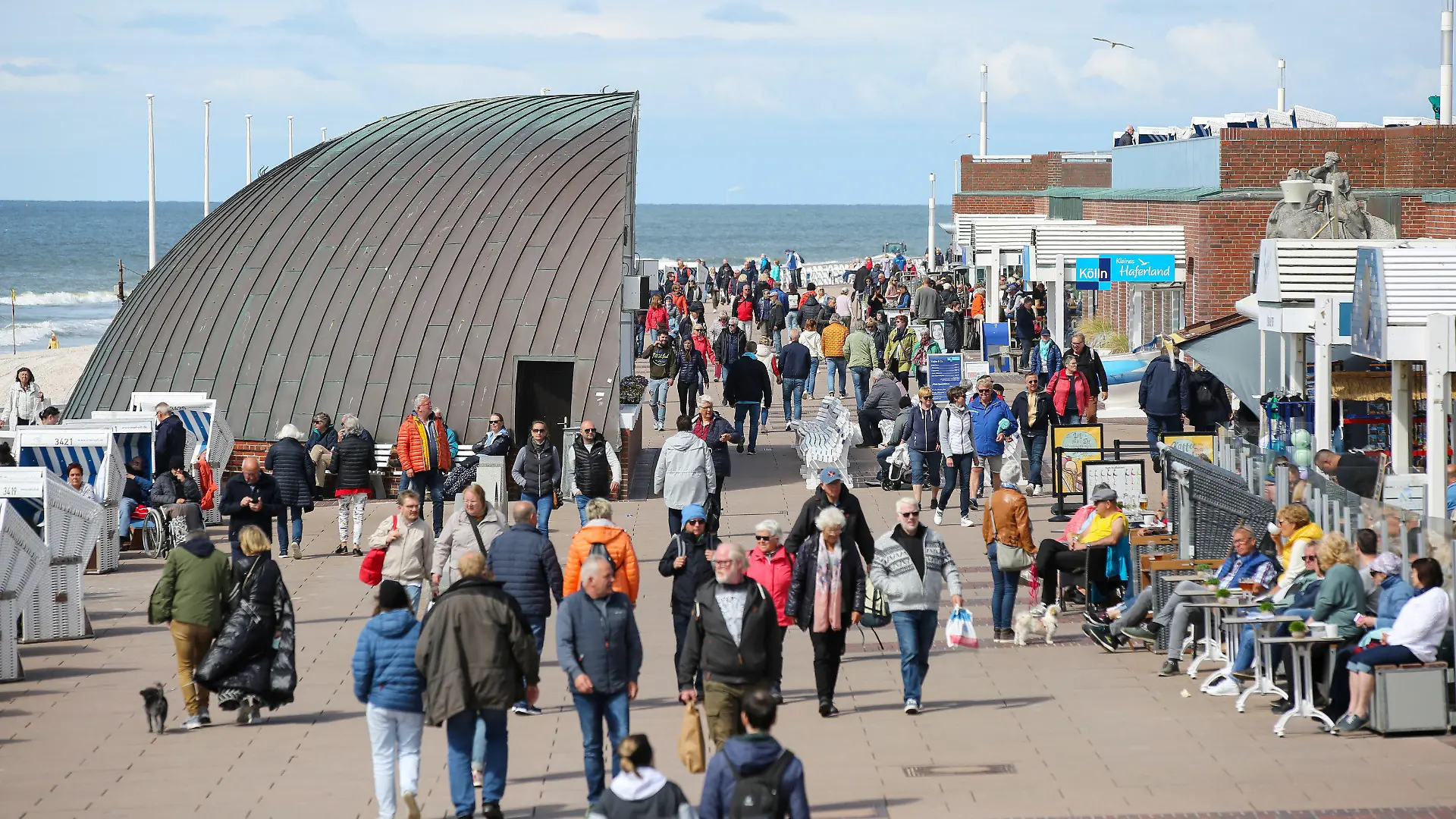 PRODUKTION - 30.05.2022, Schleswig-Holstein, Westerland: Besucher sind auf der Kurpromenade von Westerland bei der "Musikmuschel" unterwegs. Mit dem Start des 9-Euro-Tickets ab dem 1. Juni 2022 werden auch mehr Besucher auf der Insel erwartet.  (zu dpa: «Pfingsten - Sylt bereitet sich auf zusätzliche Besucher vor») Foto: Bodo Marks/Bodo Marks/dpa +++ dpa-Bildfunk +++