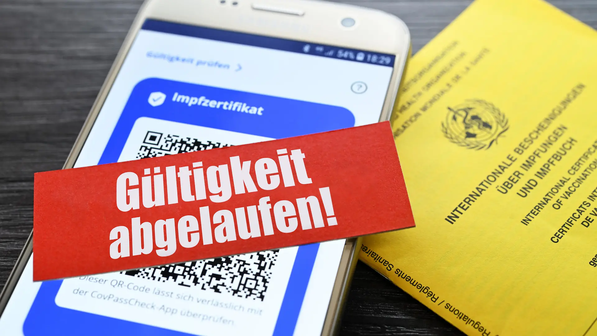 Digitales Impfzertifikat auf Smartphone und Schriftzug Gültigkeit abgelaufen