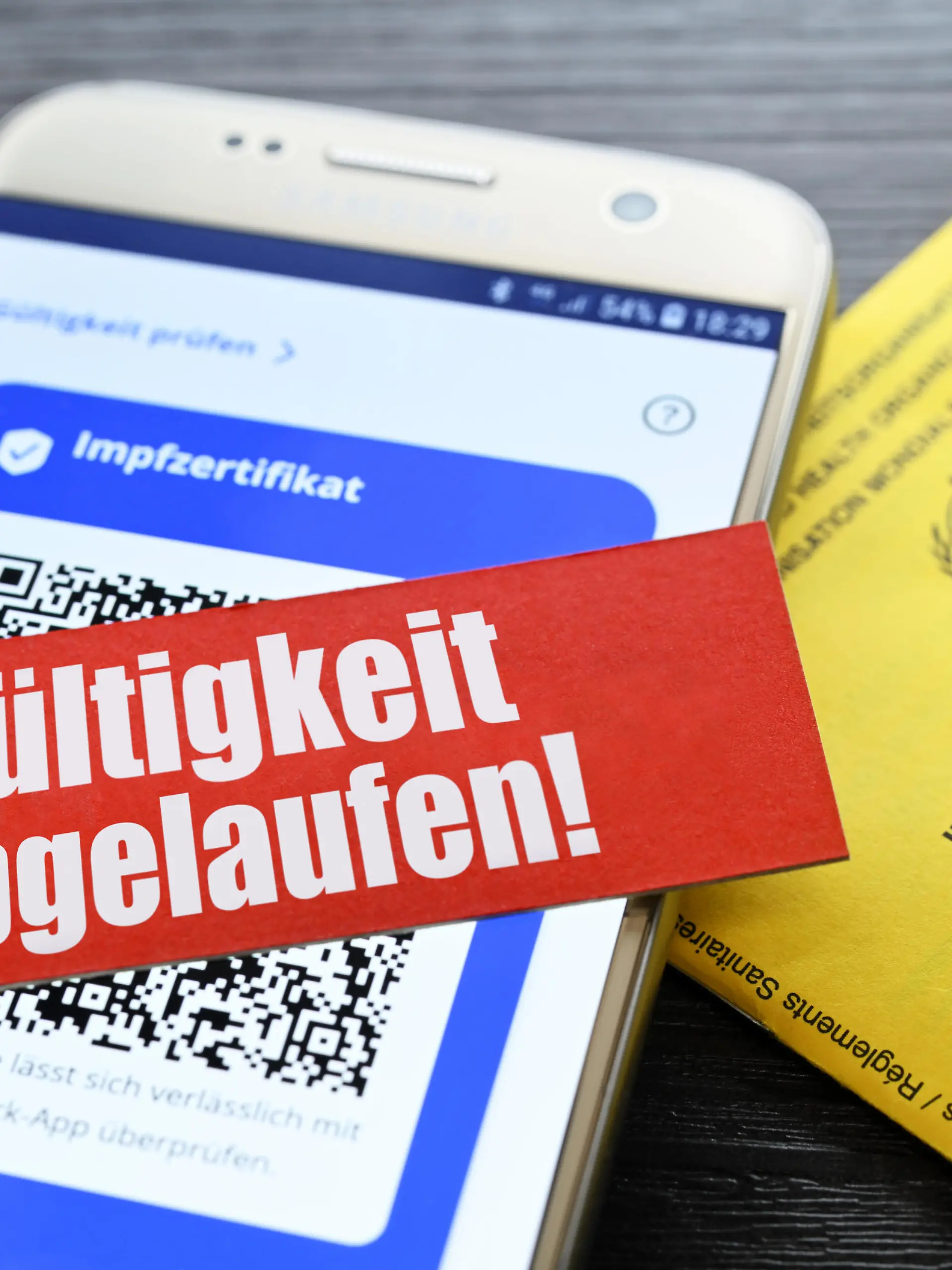 Digitales Impfzertifikat auf Smartphone und Schriftzug Gültigkeit abgelaufen