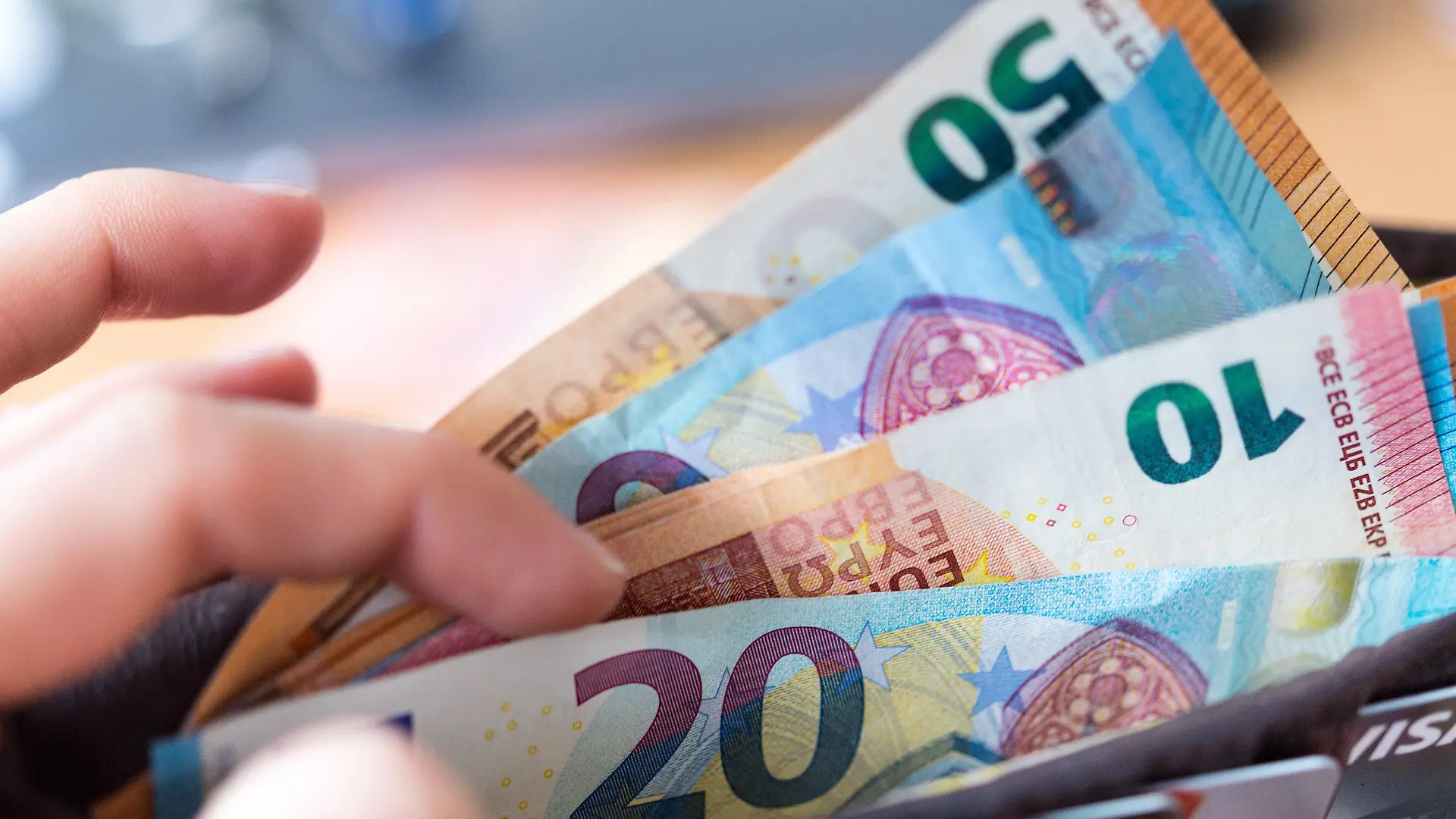 ARCHIV - 04.12.2018, Sachsen, Dresden: Eine Frau hält ein Portemonnaie in der Hand, in dem Geldscheine stecken. Die Caritas und die Deutsche Bank bescheren ihre Beschäftigten mit einem steuerfreien Zuschuss als Inflationsausgleich, ebenso wie viele weitere Arbeitgeber.(zu dpa «Extra-Geld vom Chef als Inflationsausgleich») Foto: Monika Skolimowska/dpa-Zentralbild/dpa +++ dpa-Bildfunk +++